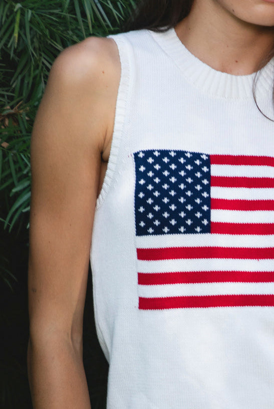 Woman wearing LIBBY American flag sweater knit tank featuring soft breathable 100% cotton sweater knit fabric, clean fitted silhouette, classic crew neckline, sleeveless design, American flag knit graphic across the front, ribbed trim along the neckline and armholes, and ribbed hem for a structured finish.