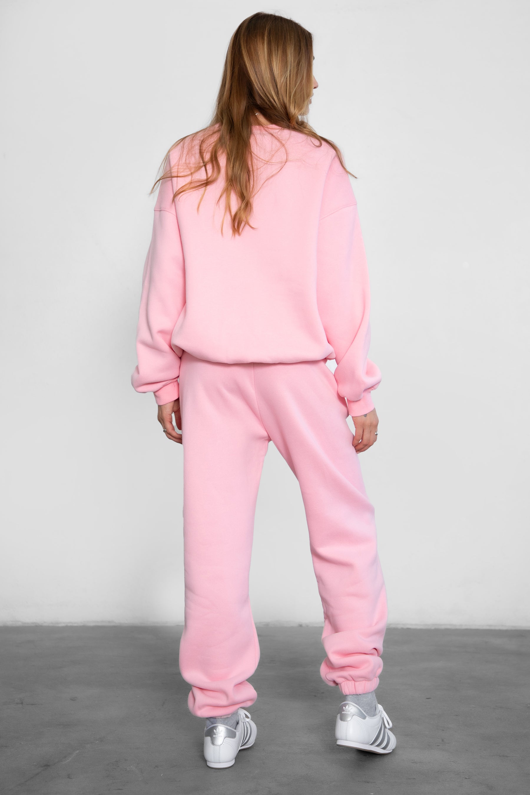 Person wearing a pink tracksuit against a plain background