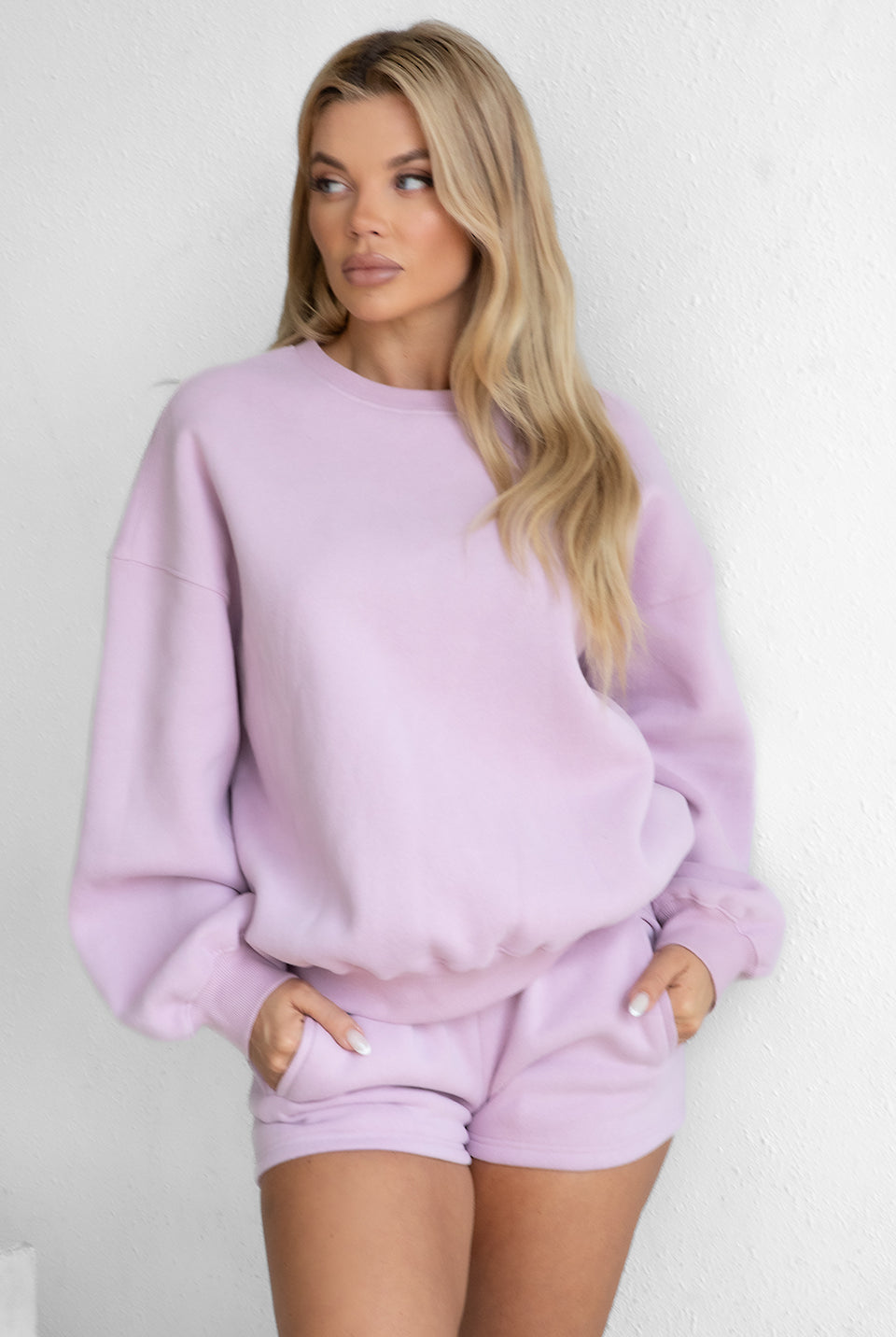 Woman wearing a lavender sweatshirt and shorts set against a white background