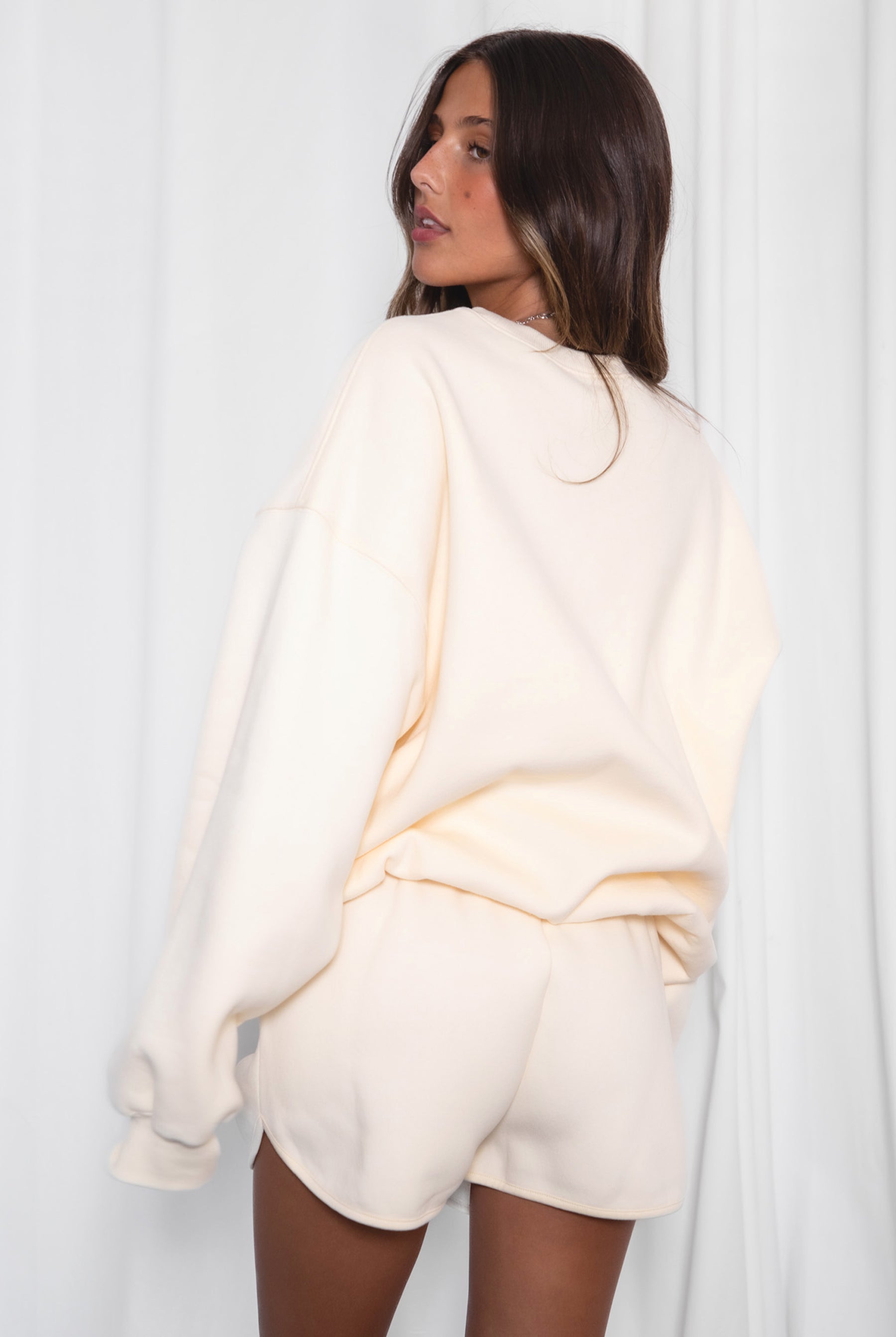 Woman wearing a cream-colored outfit against a white background