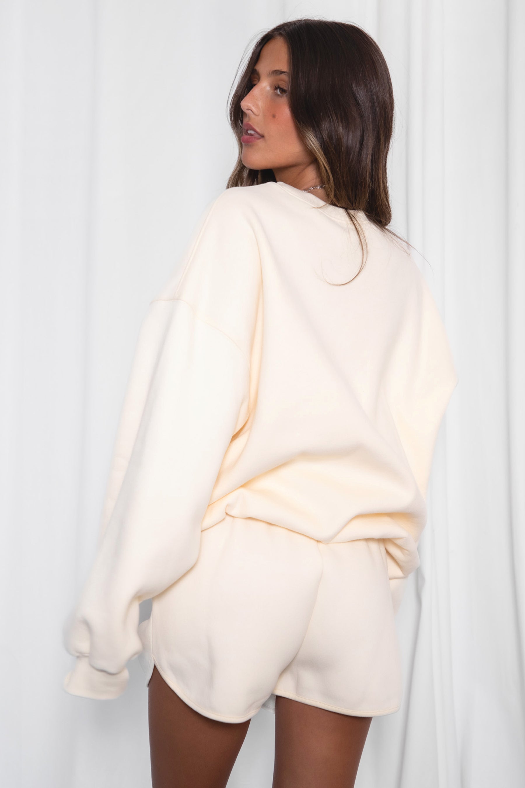 Woman wearing a cream-colored outfit against a white background