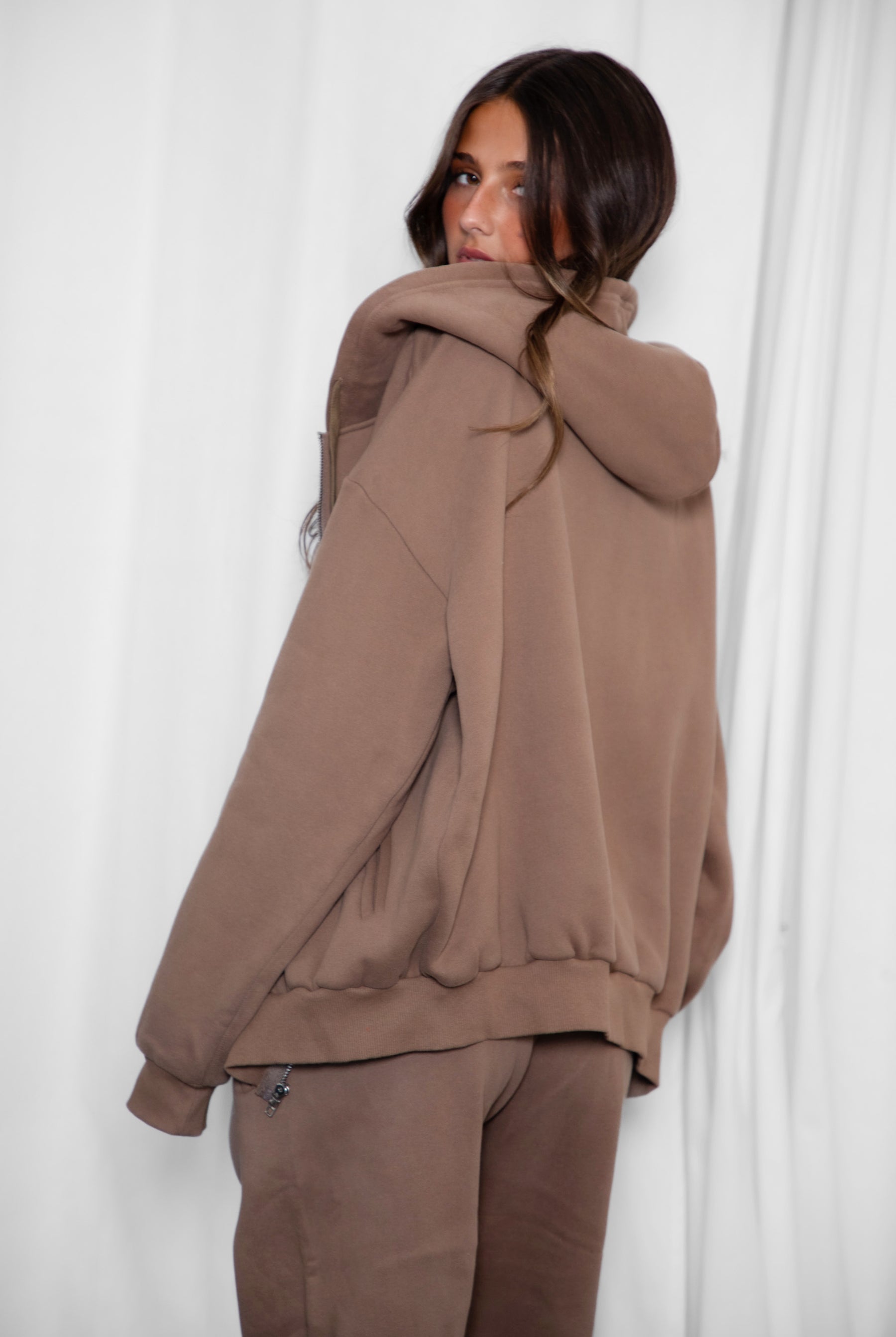 Person wearing a brown tracksuit against a white background