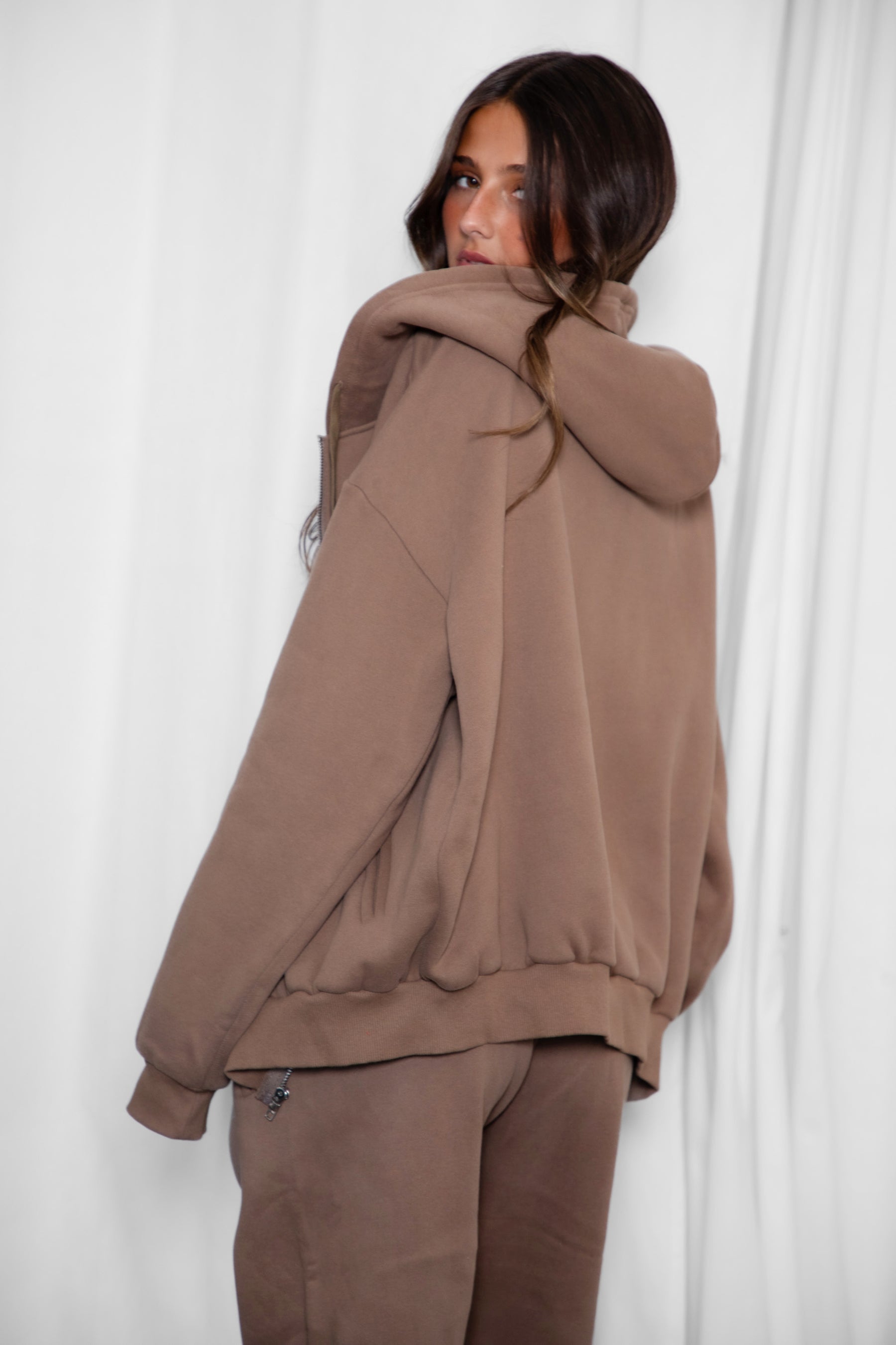 Person wearing a brown tracksuit against a white background