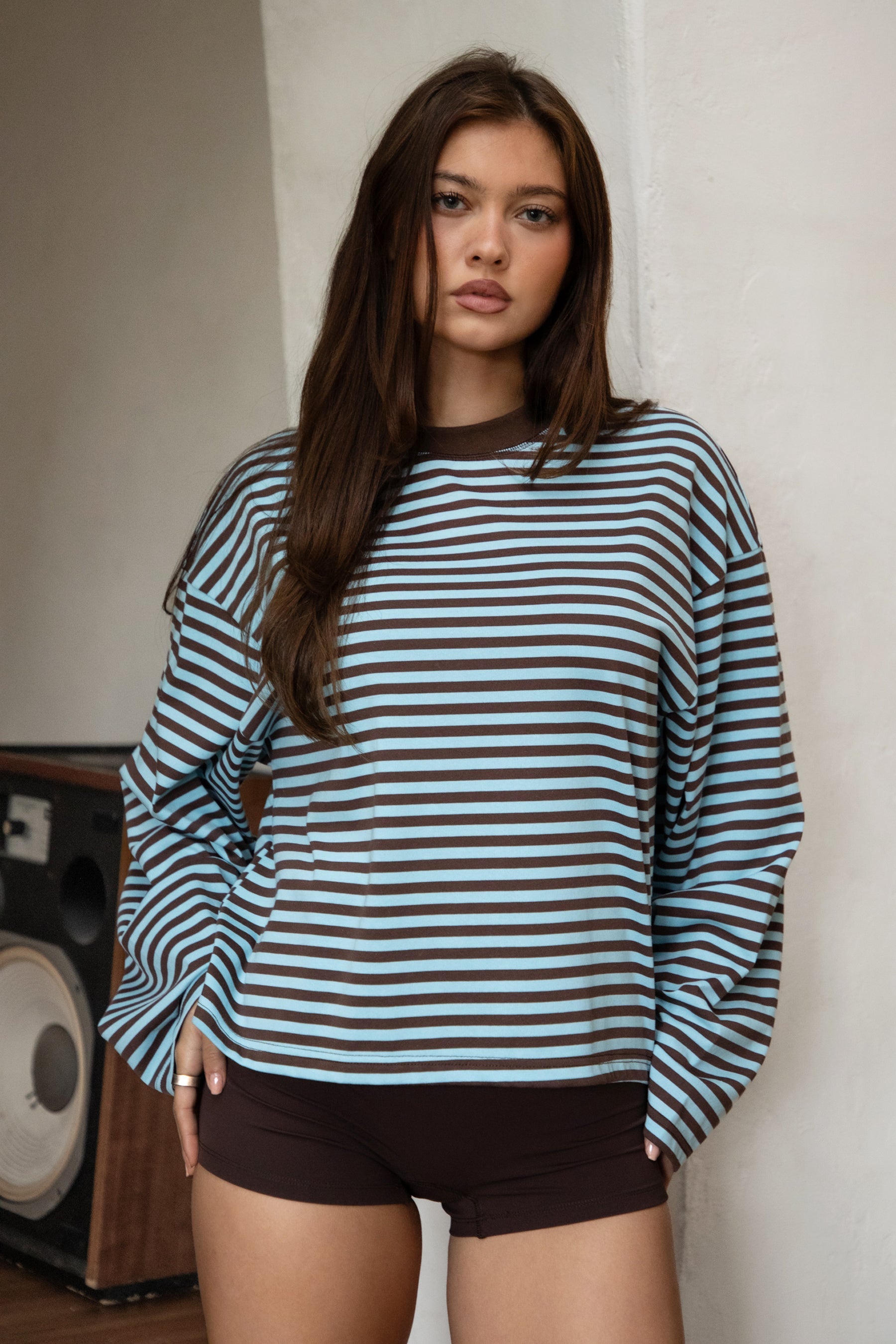Woman wearing TIC TOC TH31849 MARLOWE striped long sleeve top with a classic crew neckline, relaxed semi-oversized fit, easy drop shoulders, and soft horizontal stripes paired with dark denim jeans in a casual outdoor street setting.