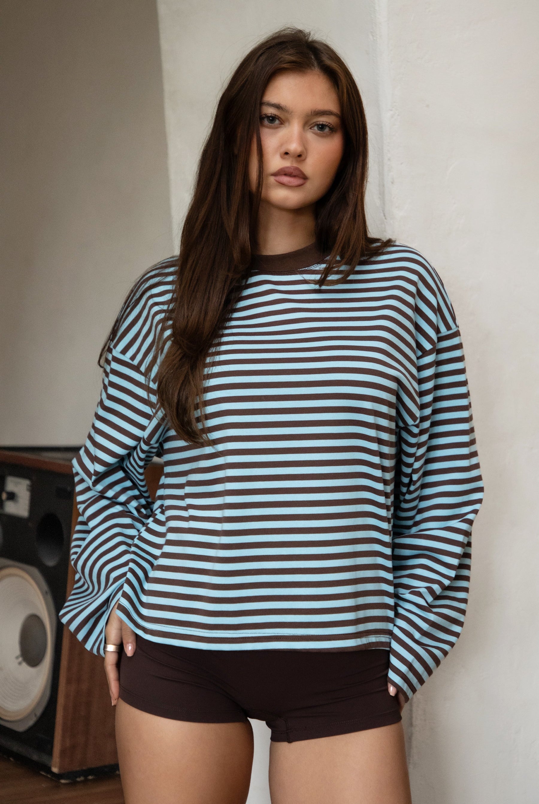 Woman wearing TIC TOC TH31849 MARLOWE striped long sleeve top with a classic crew neckline, relaxed semi-oversized fit, easy drop shoulders, and soft horizontal stripes paired with dark denim jeans in a casual outdoor street setting.