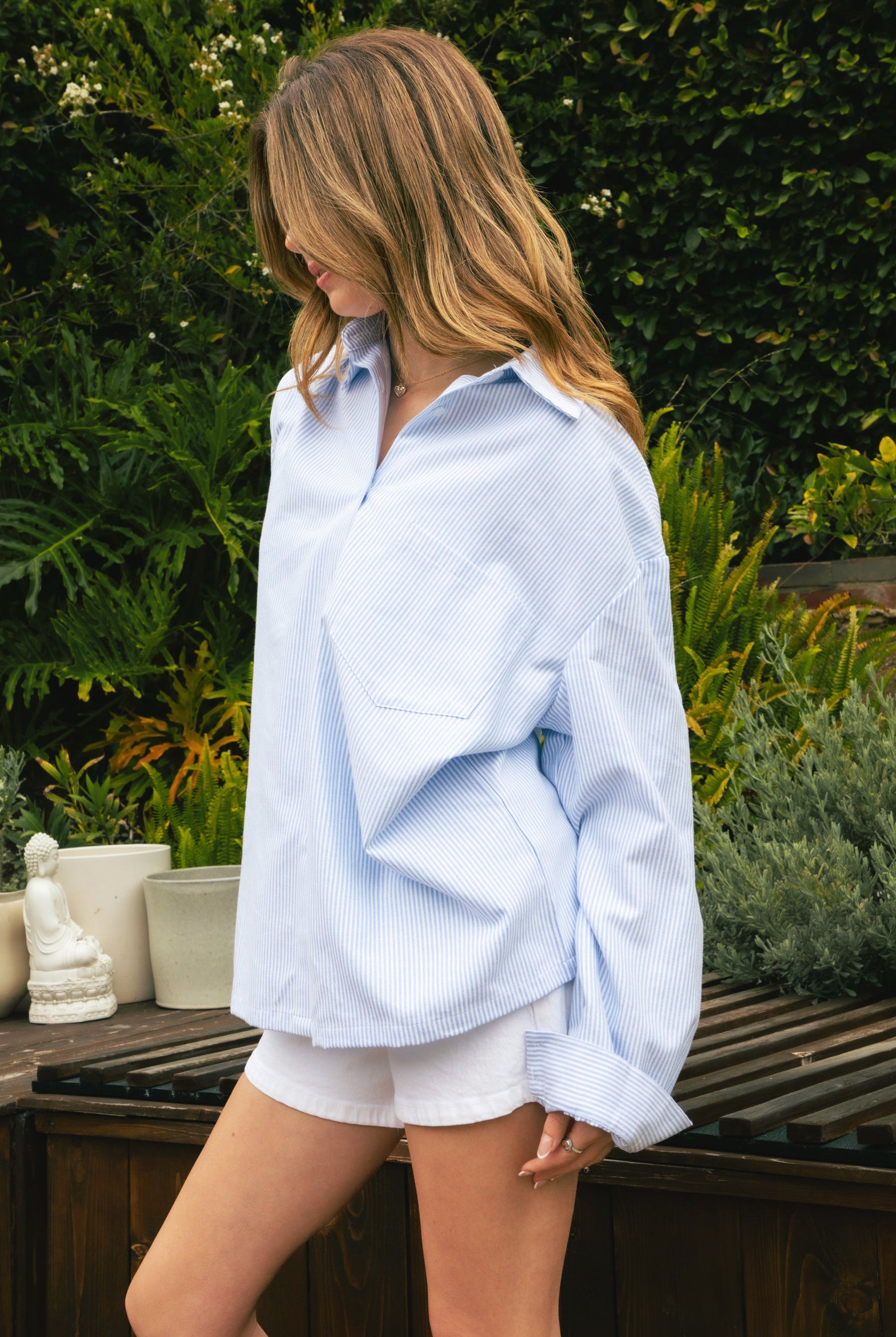 Woman wearing BLAIRE stripe oversized button down shirt featuring classic stripe oxford fabric, relaxed oversized silhouette, collared neckline, full front button closure, dropped shoulders, long sleeves with button cuffs, and functional chest pocket for effortless layering.