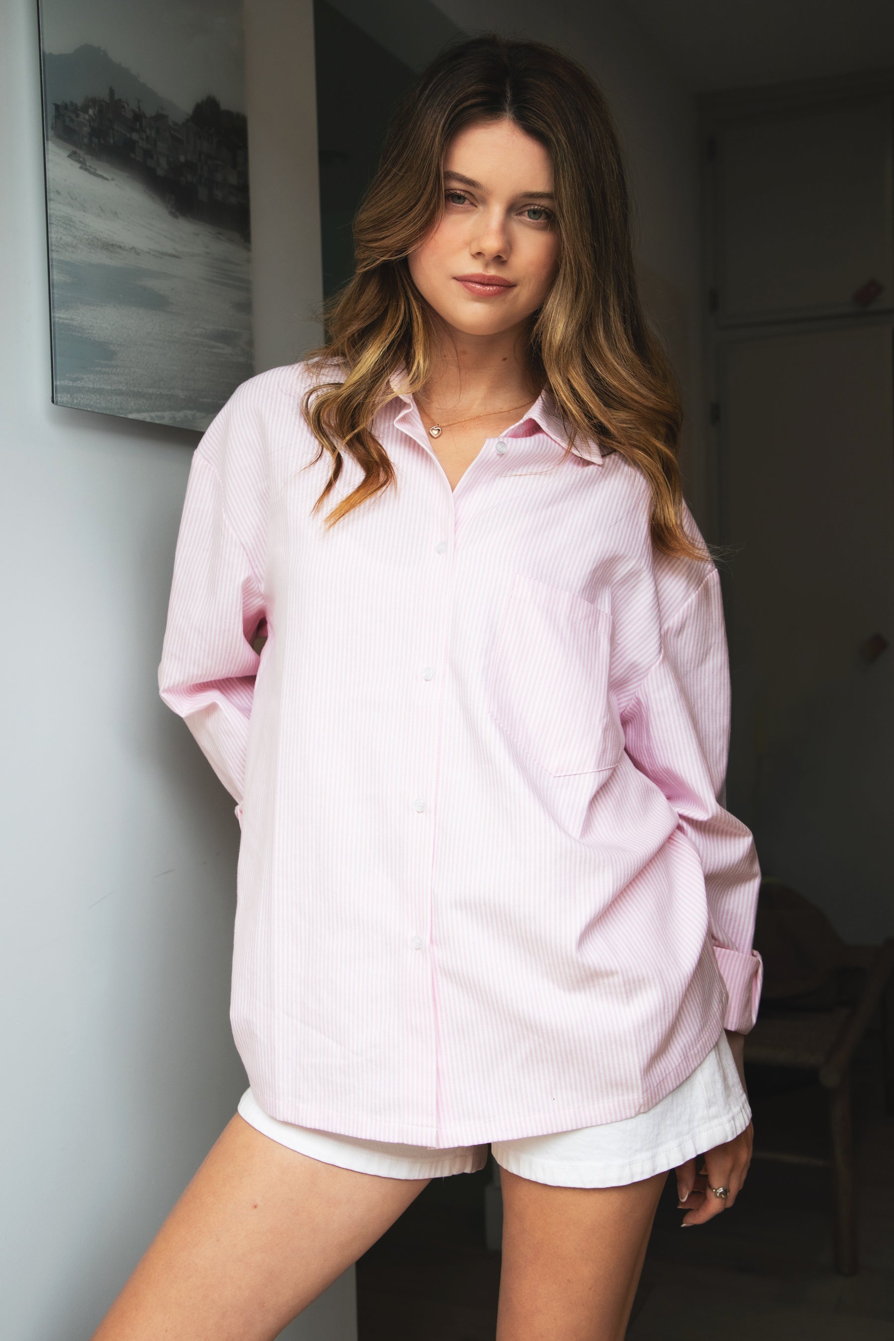 Woman wearing BLAIRE stripe oversized button down shirt featuring classic stripe oxford fabric, relaxed oversized silhouette, collared neckline, full front button closure, dropped shoulders, long sleeves with button cuffs, and functional chest pocket for effortless layering.