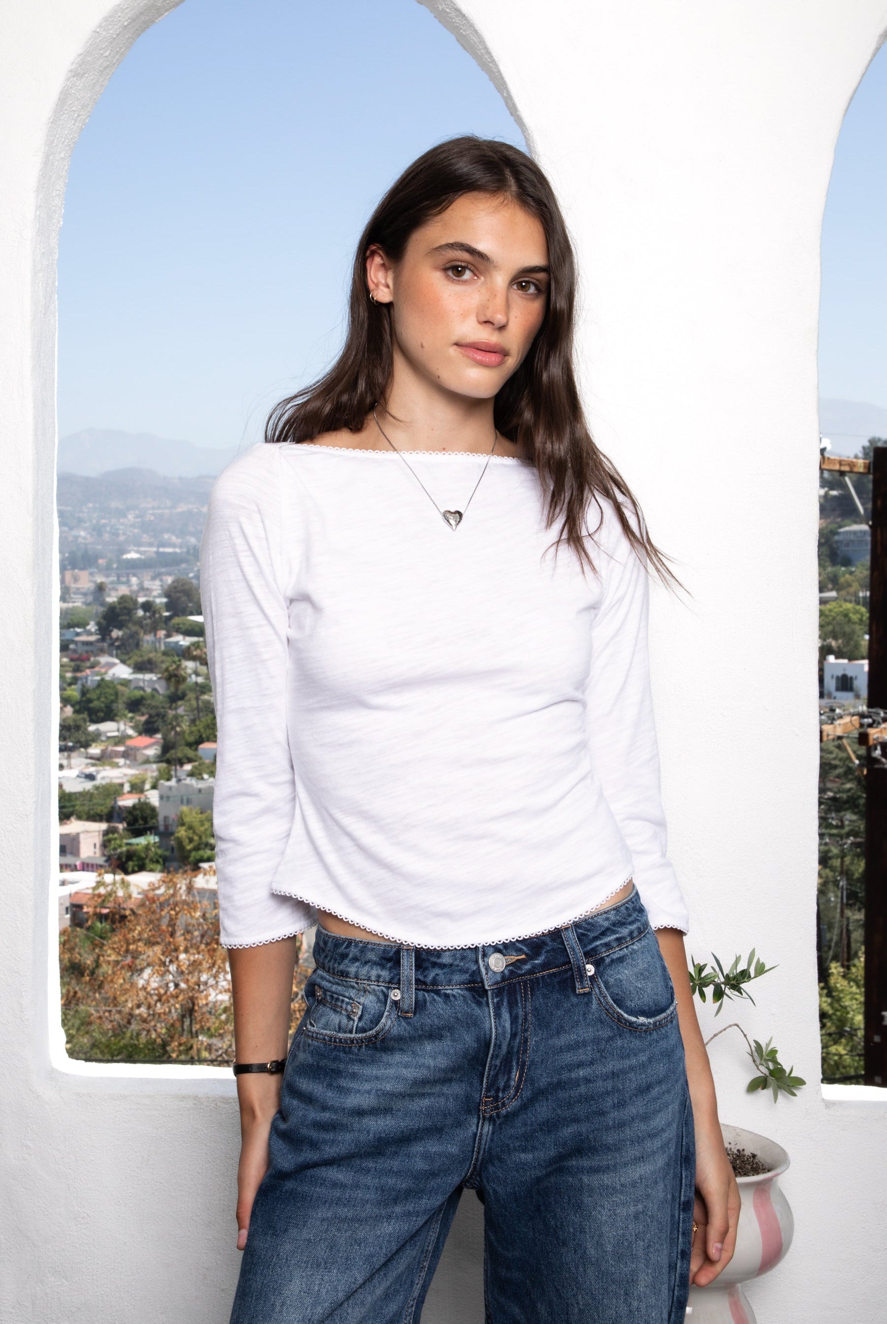 Woman wearing LUMA cotton rib three quarter sleeve boat neck top featuring soft cotton slub jersey, lightweight breathable feel, classic boat neckline, delicate picot trim, three quarter sleeves with matching cuff trim, picot trim hem, relaxed slim fit, and subtle curved hem.