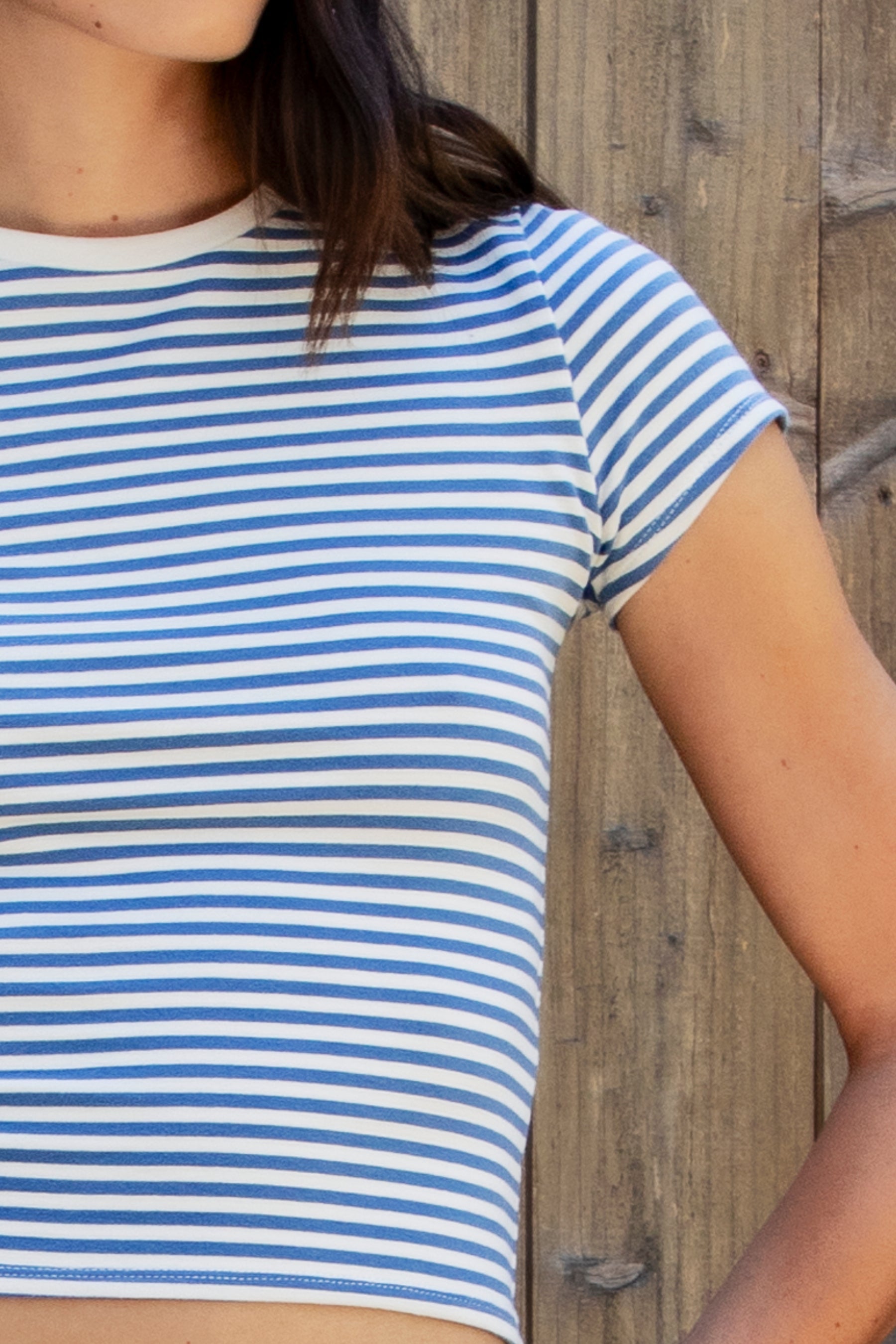 Woman wearing BRISA French terry stripe crewneck short sleeve top featuring soft stretch French terry fabric, classic crewneck design, contrast neckband detail, slim fitted short sleeves, timeless yarn dye stripe pattern, and semi cropped length for easy everyday styling.