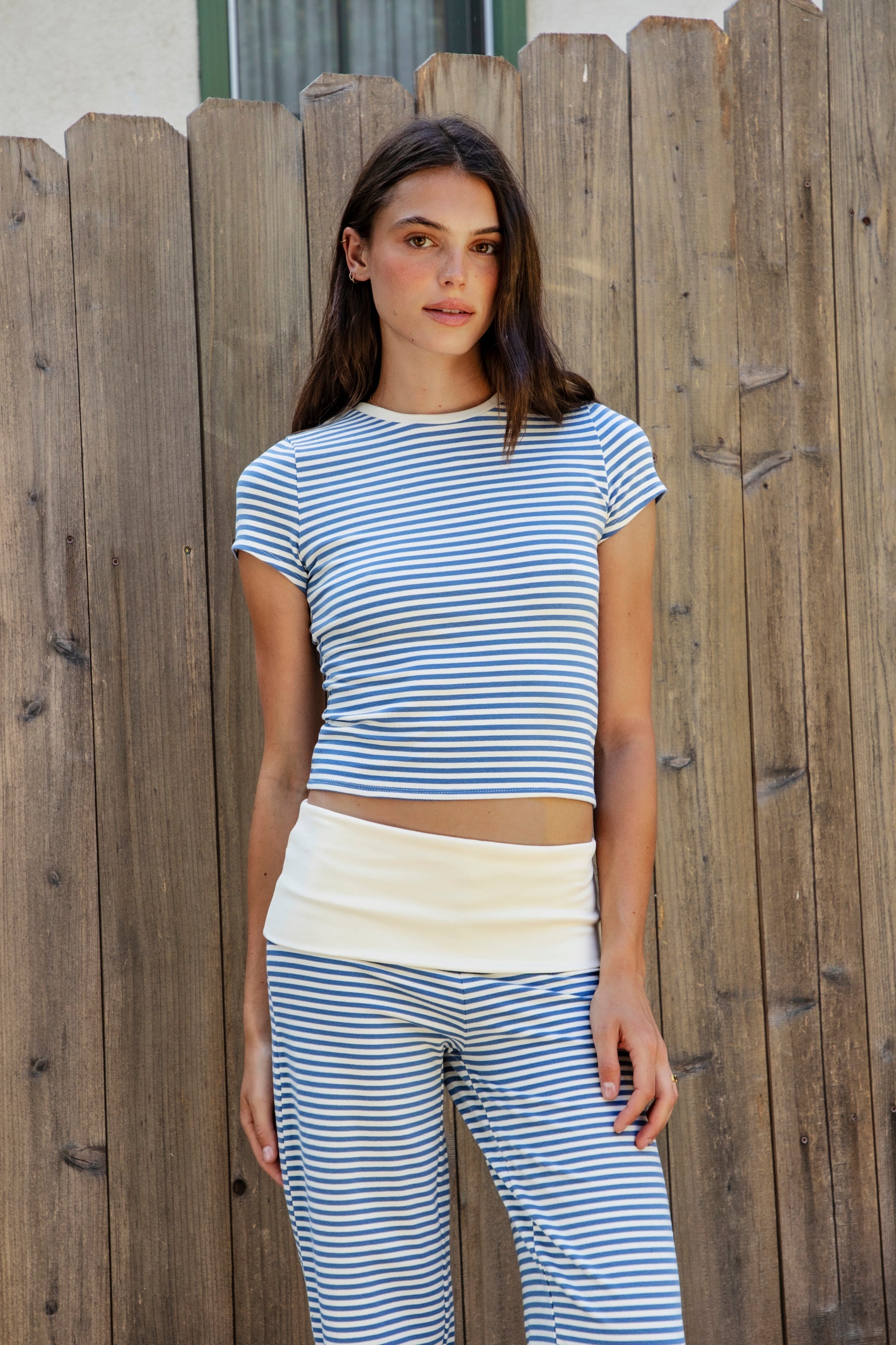 Woman wearing BRISA French terry stripe crewneck short sleeve top featuring soft stretch French terry fabric, classic crewneck design, contrast neckband detail, slim fitted short sleeves, timeless yarn dye stripe pattern, and semi cropped length for easy everyday styling.
