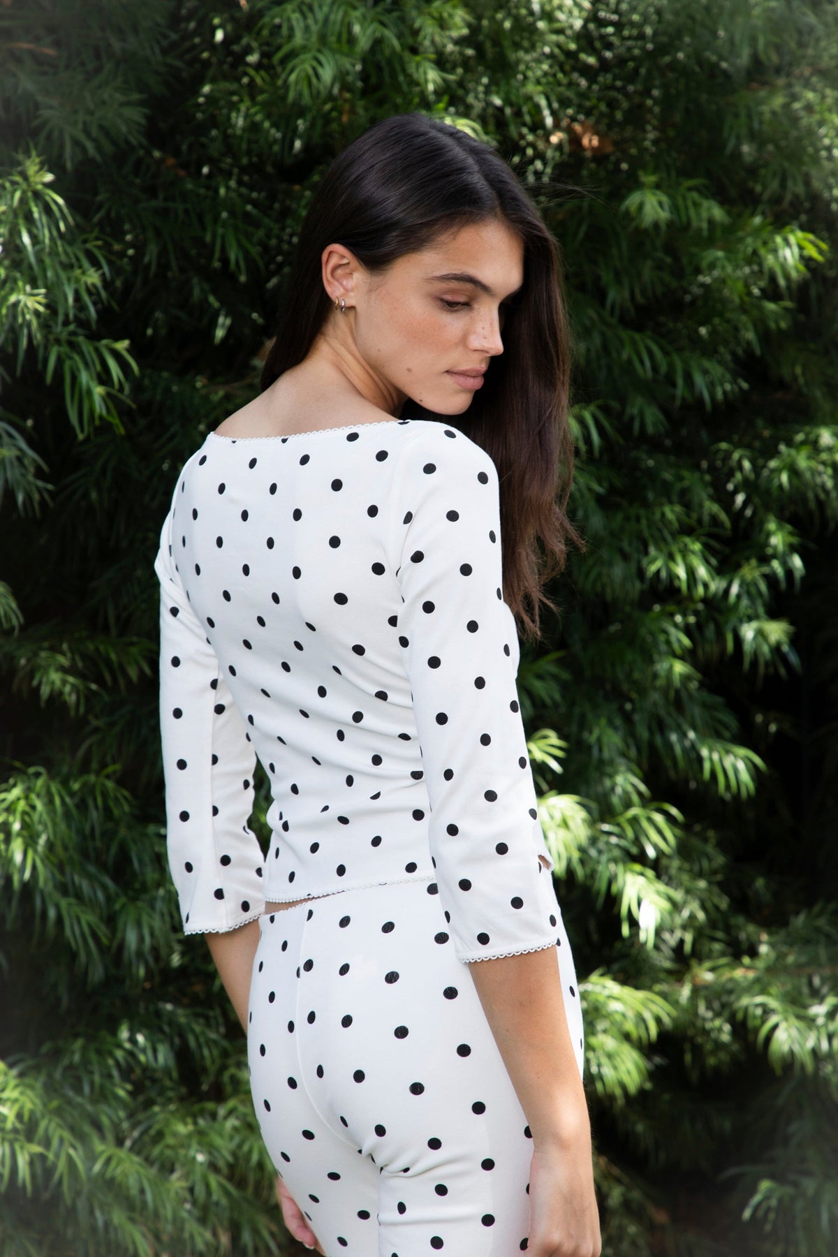 Woman wearing MARLIE polka dot quarter sleeve top featuring soft cotton blend stretch jersey fabric, allover polka dot print, classic boat neckline with delicate picot trim, fitted silhouette, three quarter length sleeves with picot trim cuffs, and slightly cropped length designed to pair with the matching MARIE capri pants.