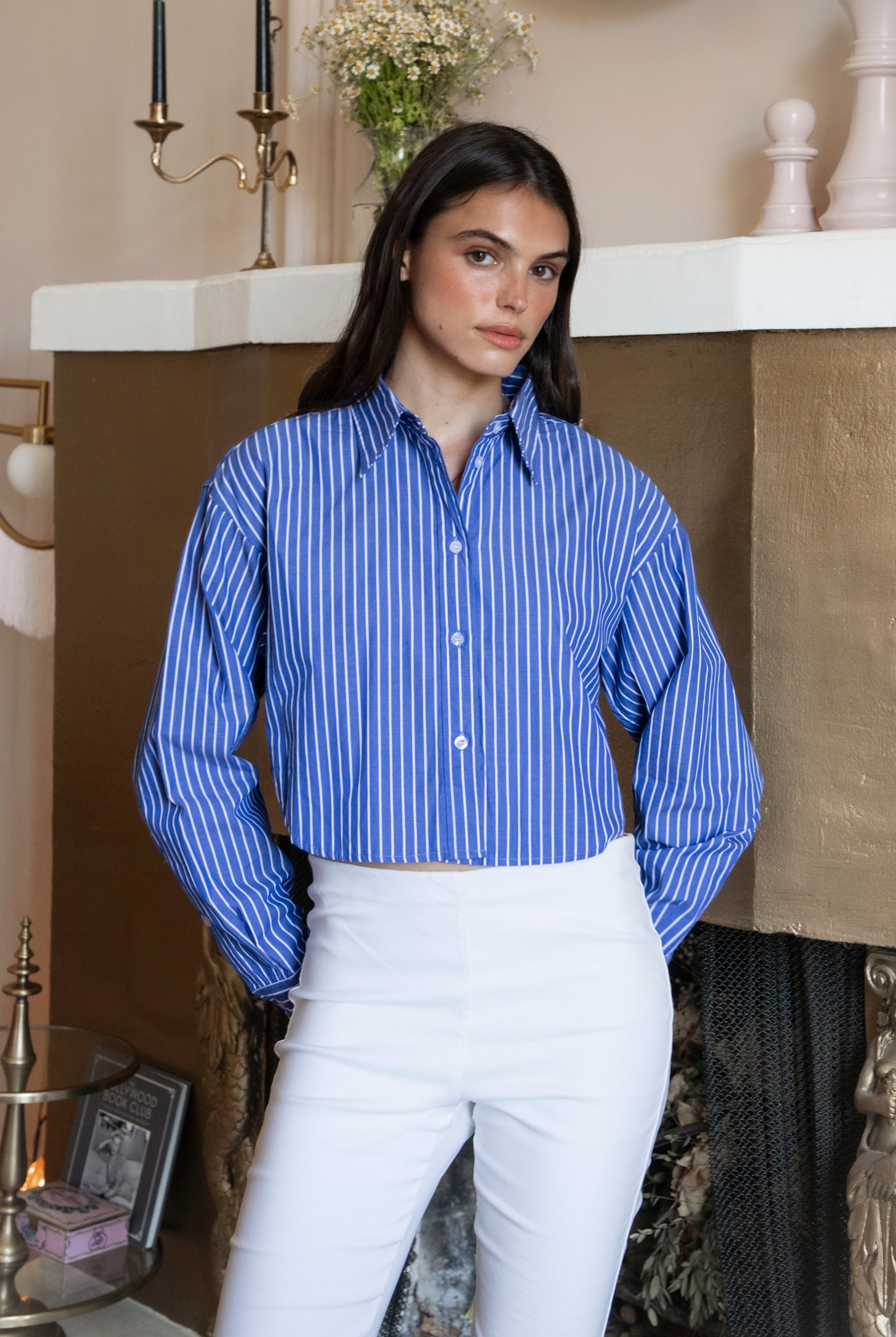 Woman wearing HAMPTON classic stripe collared cropped poplin shirt featuring classic stripe cotton fabric, crisp point collar, button front closure, ultra cropped relaxed silhouette, dropped shoulders, long sleeves with button cuffs, and clean back yoke detail for a polished modern tailored look.