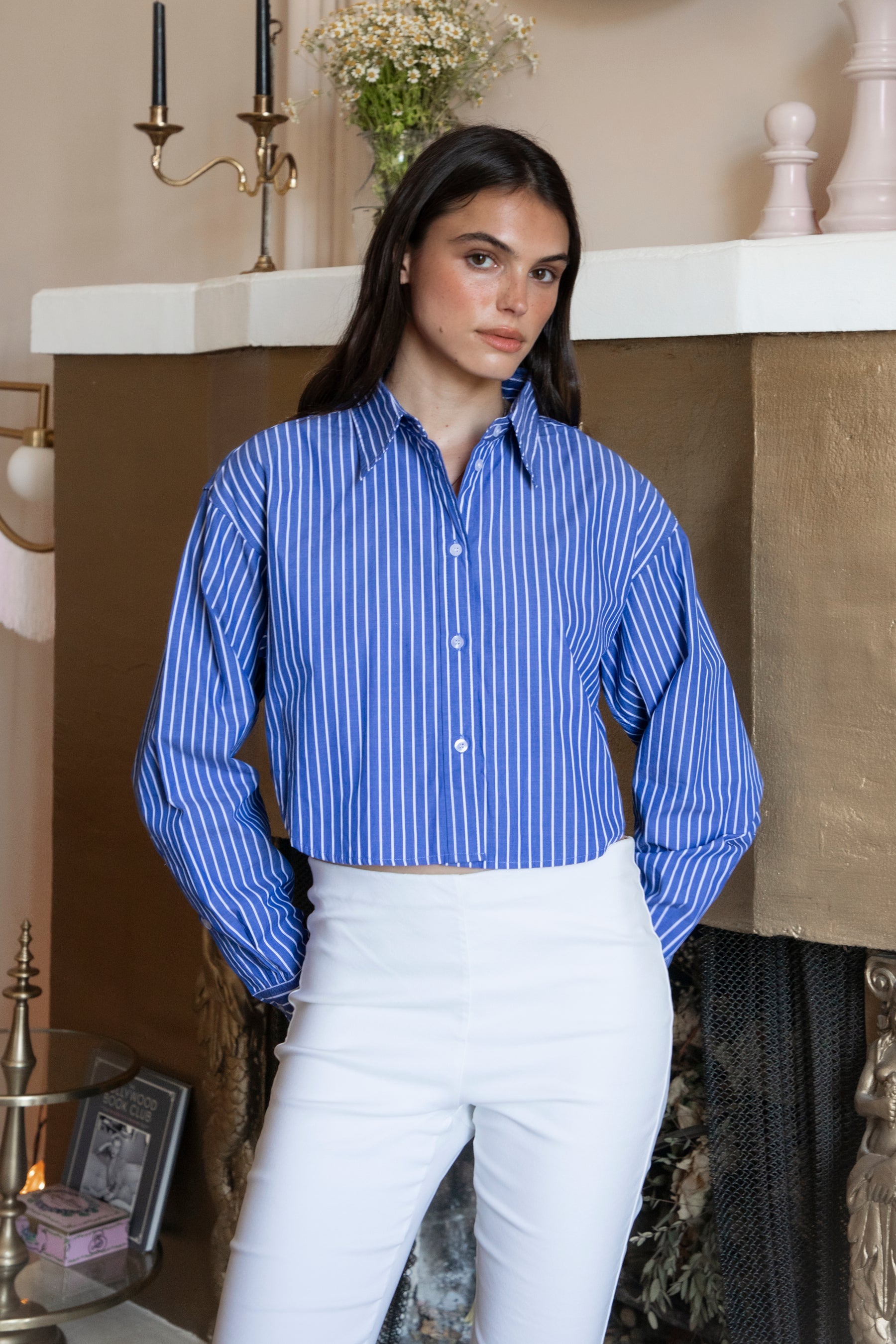 Woman wearing HAMPTON classic stripe collared cropped poplin shirt featuring classic stripe cotton fabric, crisp point collar, button front closure, ultra cropped relaxed silhouette, dropped shoulders, long sleeves with button cuffs, and clean back yoke detail for a polished modern tailored look.