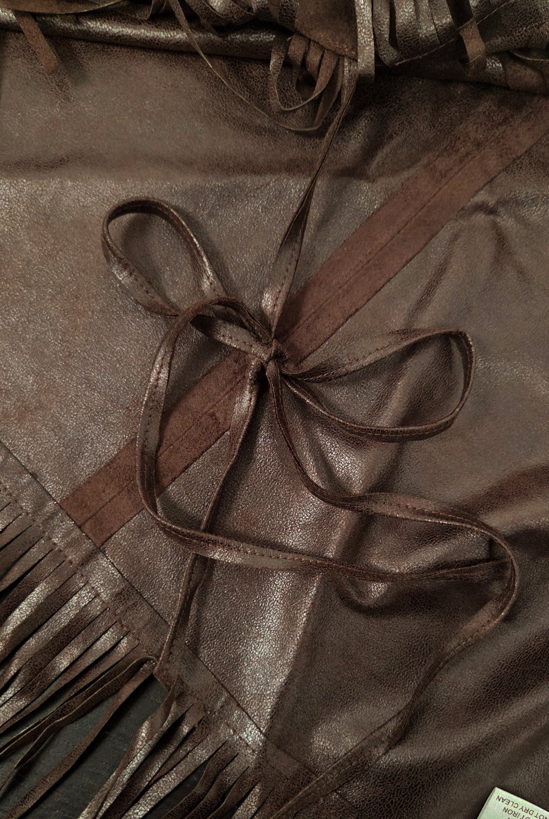 Woman wearing TIC TOC TL31825 STALLION faux suede fringe poncho featuring a cropped cape silhouette, drop shoulder relaxed fit, long fringe tassel detailing along the hem and sleeves, and a soft western-inspired faux suede texture, styled over a fitted top with denim bottoms for a rodeo festival look.