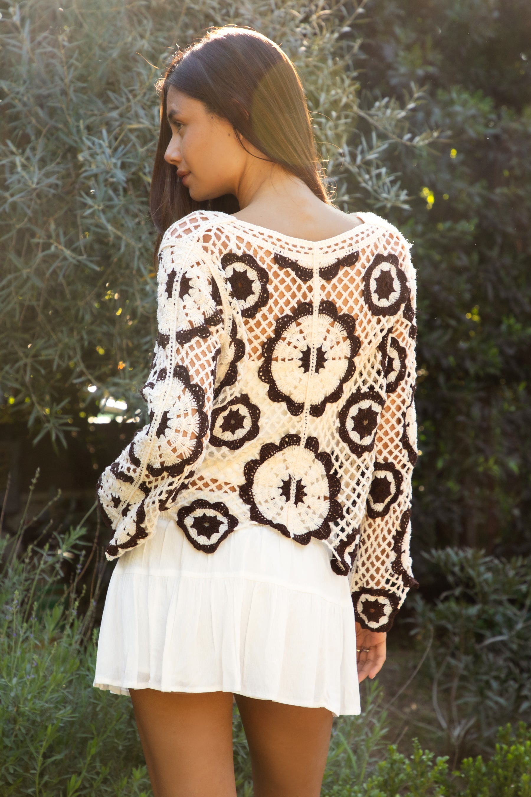 Woman wearing TIC TOC TL31962-SOLANDRA SOLANDRA crochet long sleeve cover up top featuring an open crochet mandala flower pattern in contrast cream and brown circular design, wide round neckline, relaxed easy fit silhouette, and long bell sleeves with lightweight open knit texture, styled over a simple bralette and bottoms for a boho festival and resort-ready look.