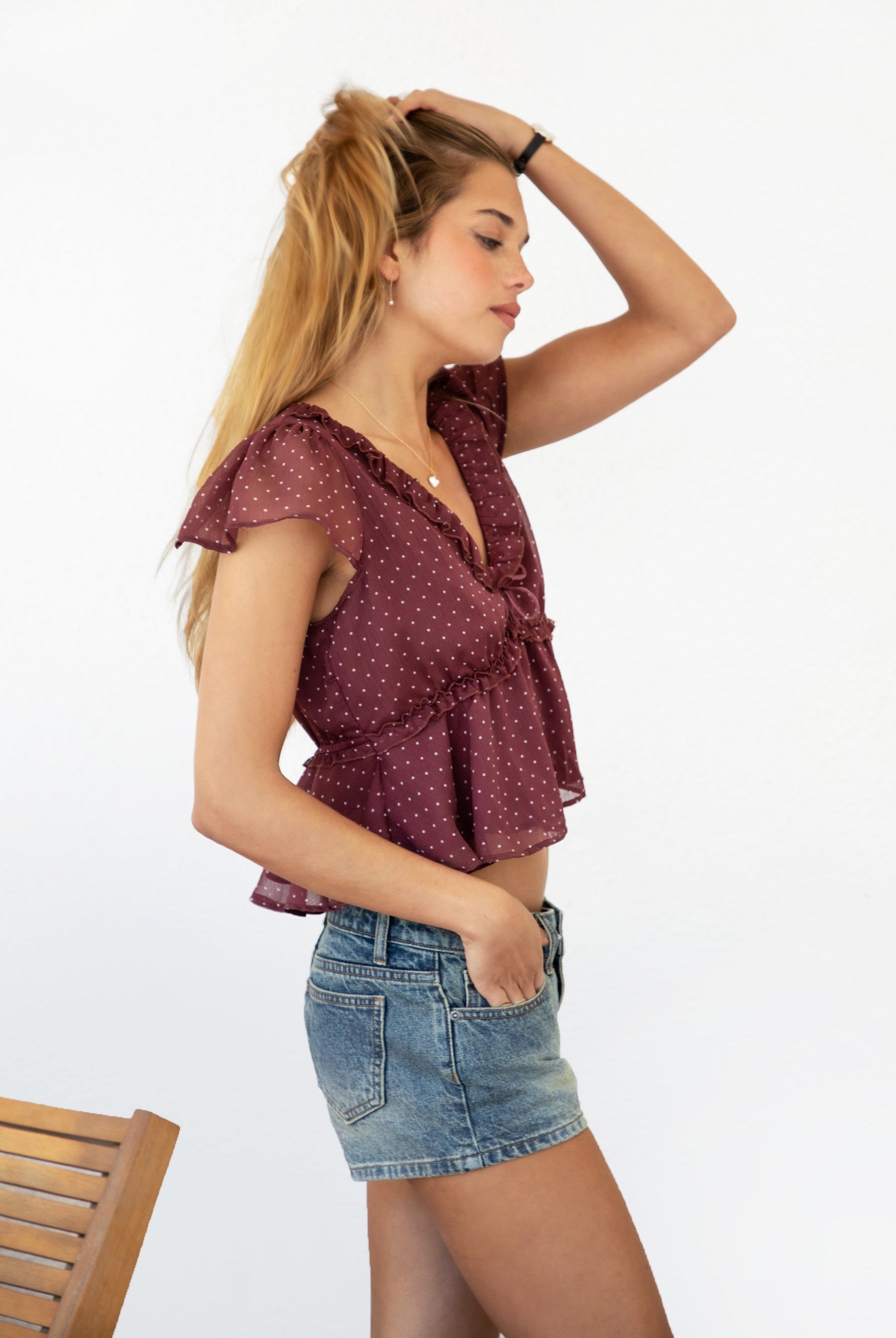Woman wearing WYNONA polka dot chiffon crop top featuring lightweight printed chiffon, V-neckline with ruffle trim, flutter sleeves, elastic underbust band, front bow detail, and a cropped peplum silhouette with full lining for comfort.