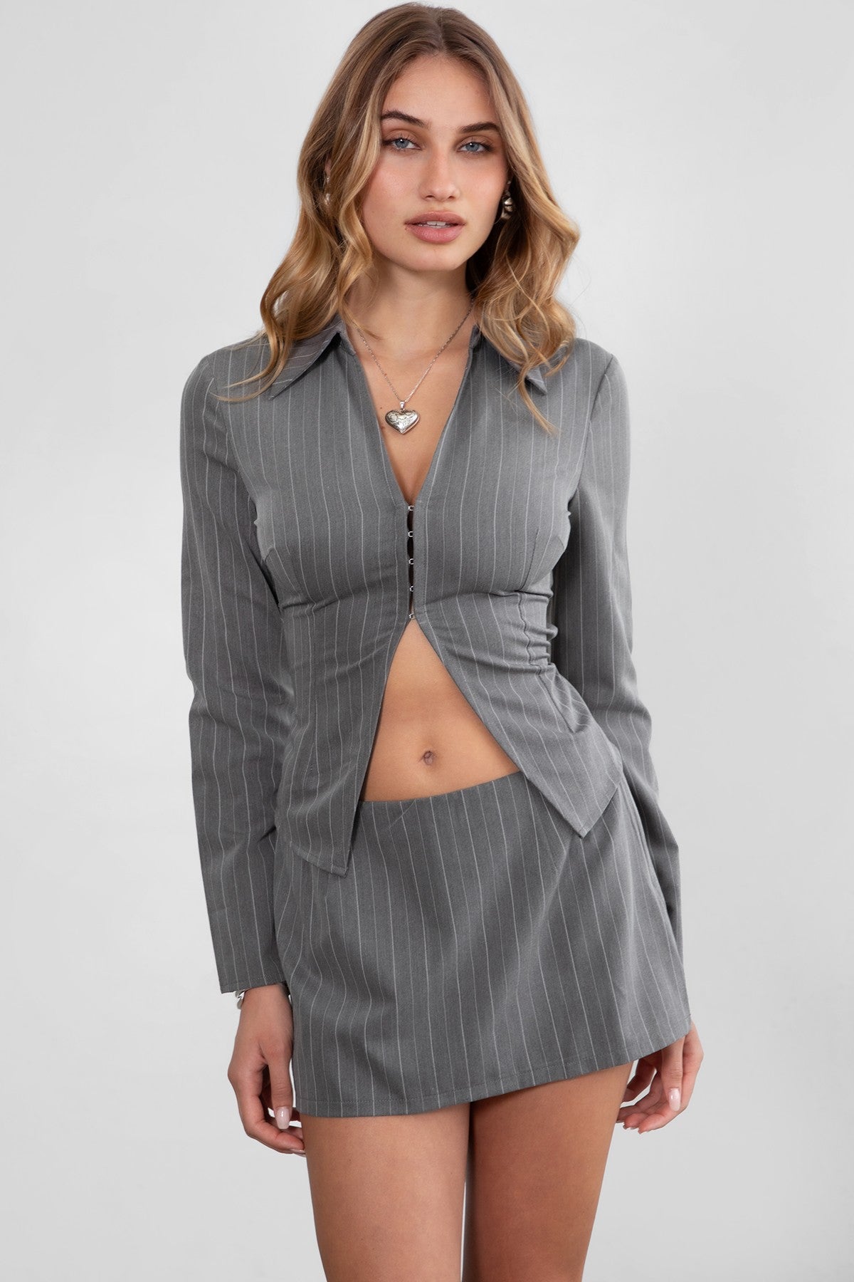GEEK Pinstripe Mini Skirt Set 
Long Sleeve Top 
Low V Collared Neckline 
With Connected Hook and Eye Closure 
Slit Open Hem Design 
Full Open Back Design 
With Connected Criss Cross Adjustable Straps 
Matching Low Rise Mini Skirt