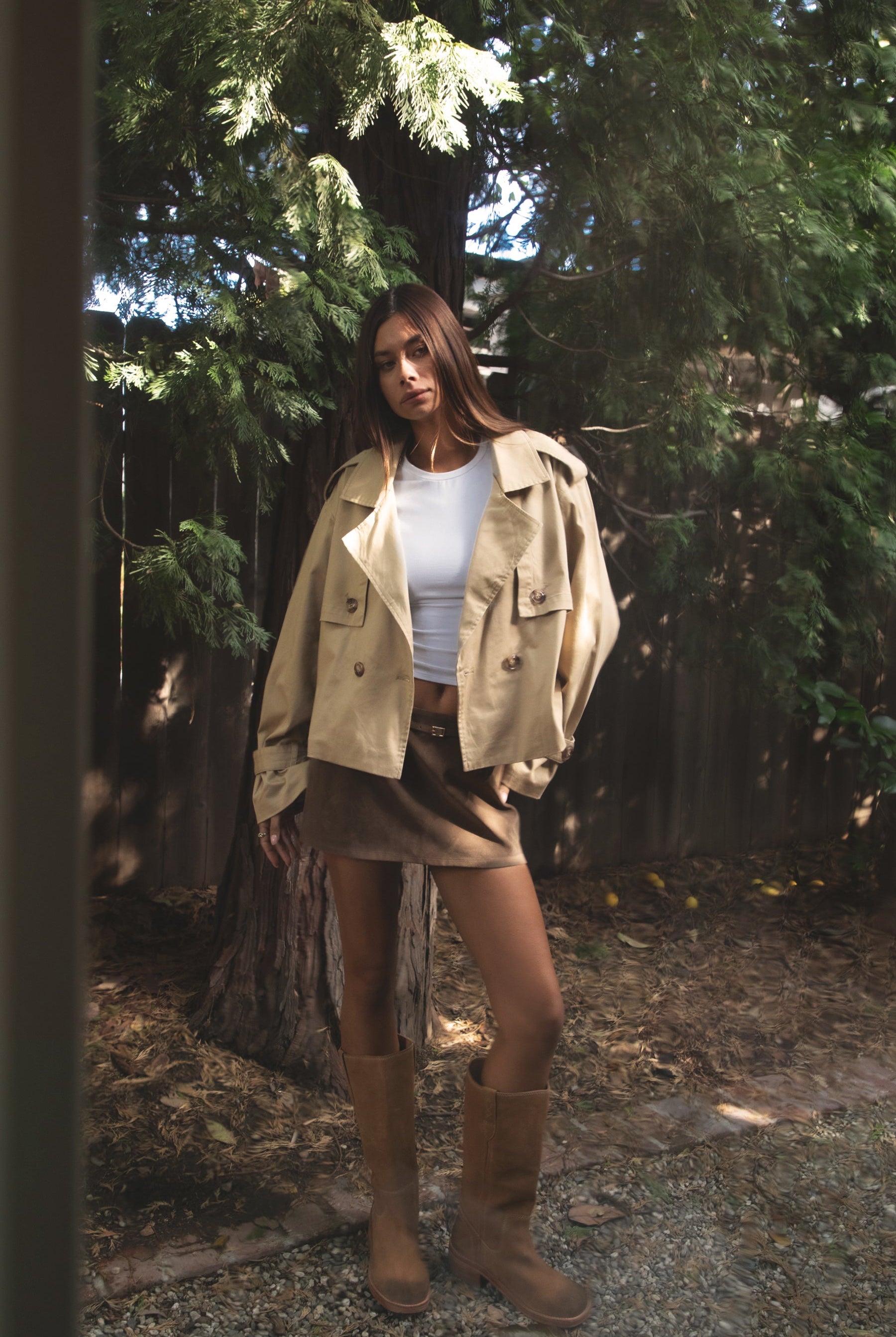 Woman wearing TIC TOC TT31828-MARAIS MARAIS oversized long sleeve cropped trench jacket featuring a double breasted front button closure, drop shoulder long sleeves with adjustable sleeve straps, removable thick self tie waist strap, and two loop holes on the back, finished with stripe voile lining inside, styled over a simple top and tailored bottoms for a Parisian chic, western-minimal layered look.