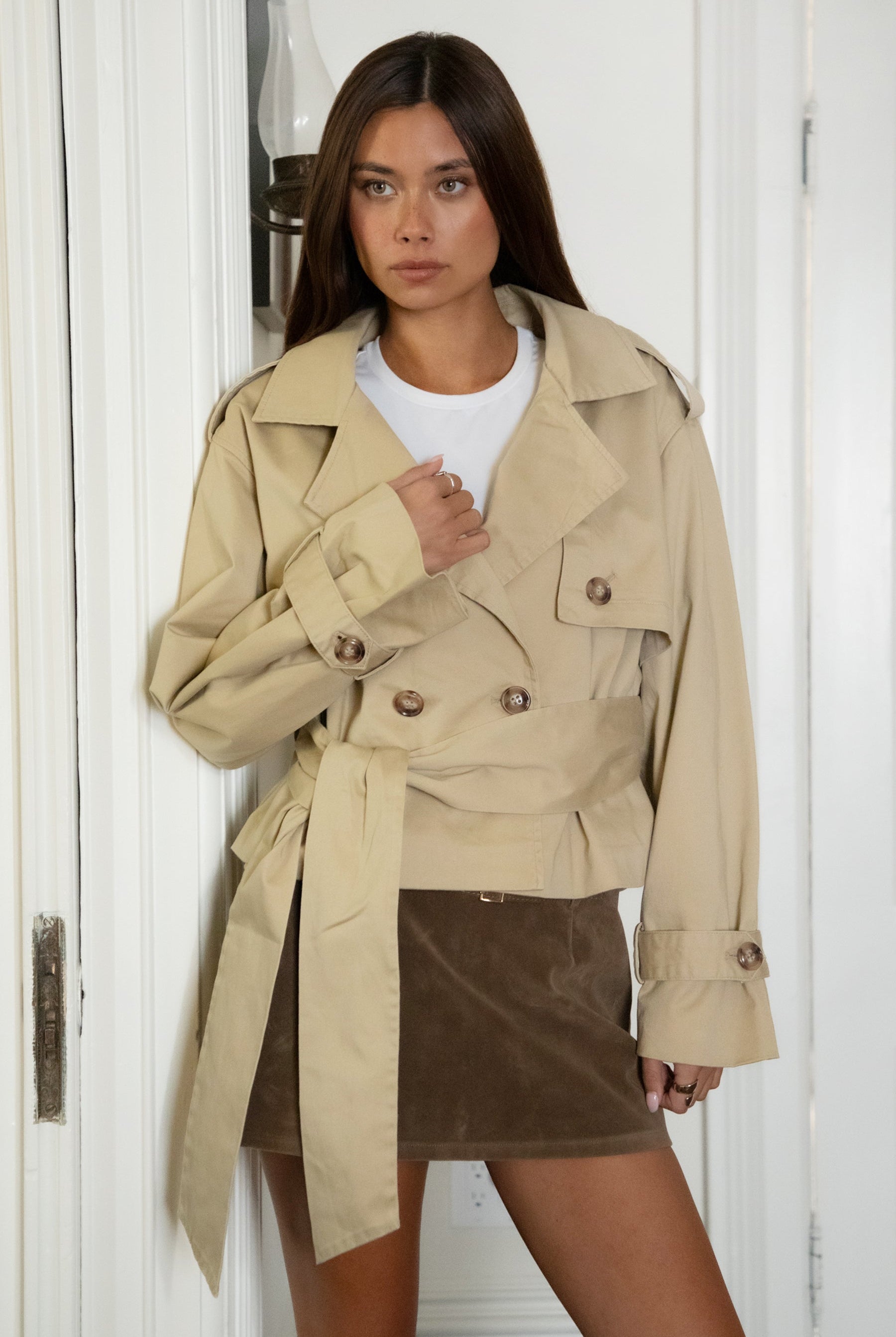 Woman wearing TIC TOC TT31828-MARAIS MARAIS oversized long sleeve cropped trench jacket featuring a double breasted front button closure, drop shoulder long sleeves with adjustable sleeve straps, removable thick self tie waist strap, and two loop holes on the back, finished with stripe voile lining inside, styled over a simple top and tailored bottoms for a Parisian chic, western-minimal layered look.
