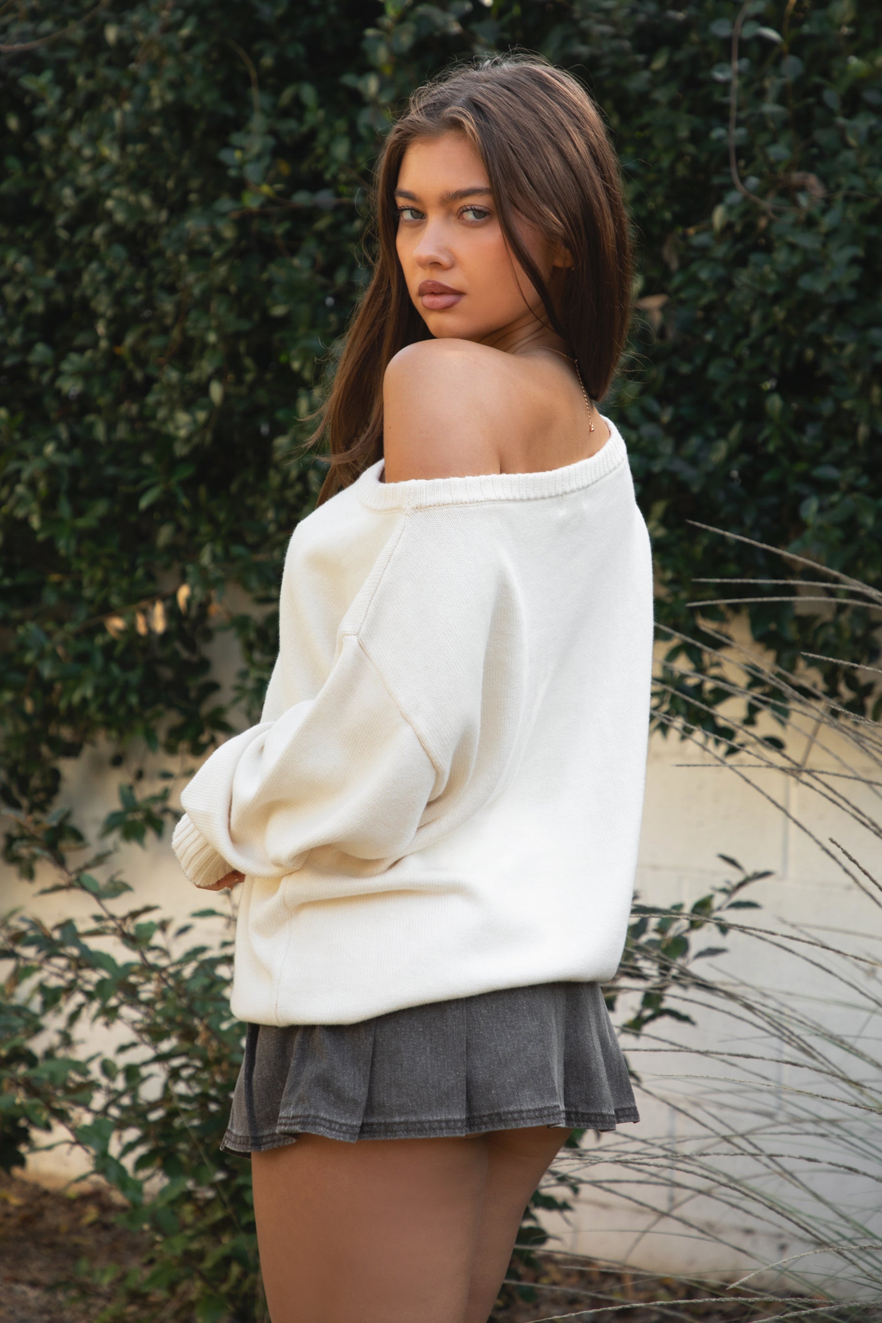 Woman wearing TIC TOC TV31893-MALTIE MALTIE knit sweater featuring a wide boat off-the-shoulder neckline, oversized relaxed fit, dropped shoulders, and long sleeves with ribbed cuffs, showcasing a poodle intarsia front graphic with American flag detailing, styled casually with denim for a cozy Americana-inspired weekend look.