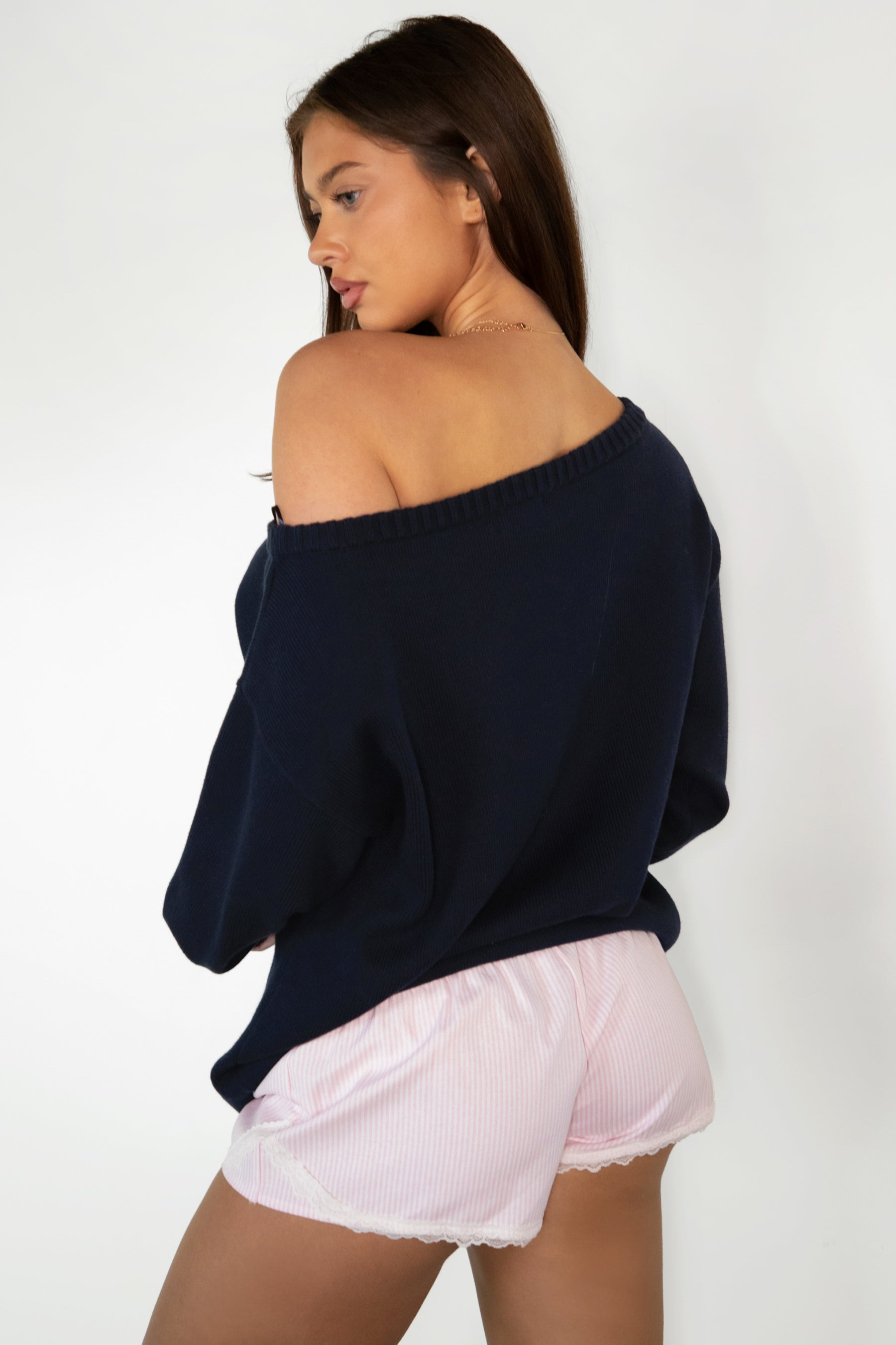 Woman wearing TIC TOC TV31893-MALTIE MALTIE knit sweater featuring a wide boat off-the-shoulder neckline, oversized relaxed fit, dropped shoulders, and long sleeves with ribbed cuffs, showcasing a poodle intarsia front graphic with American flag detailing, styled casually with denim for a cozy Americana-inspired weekend look.