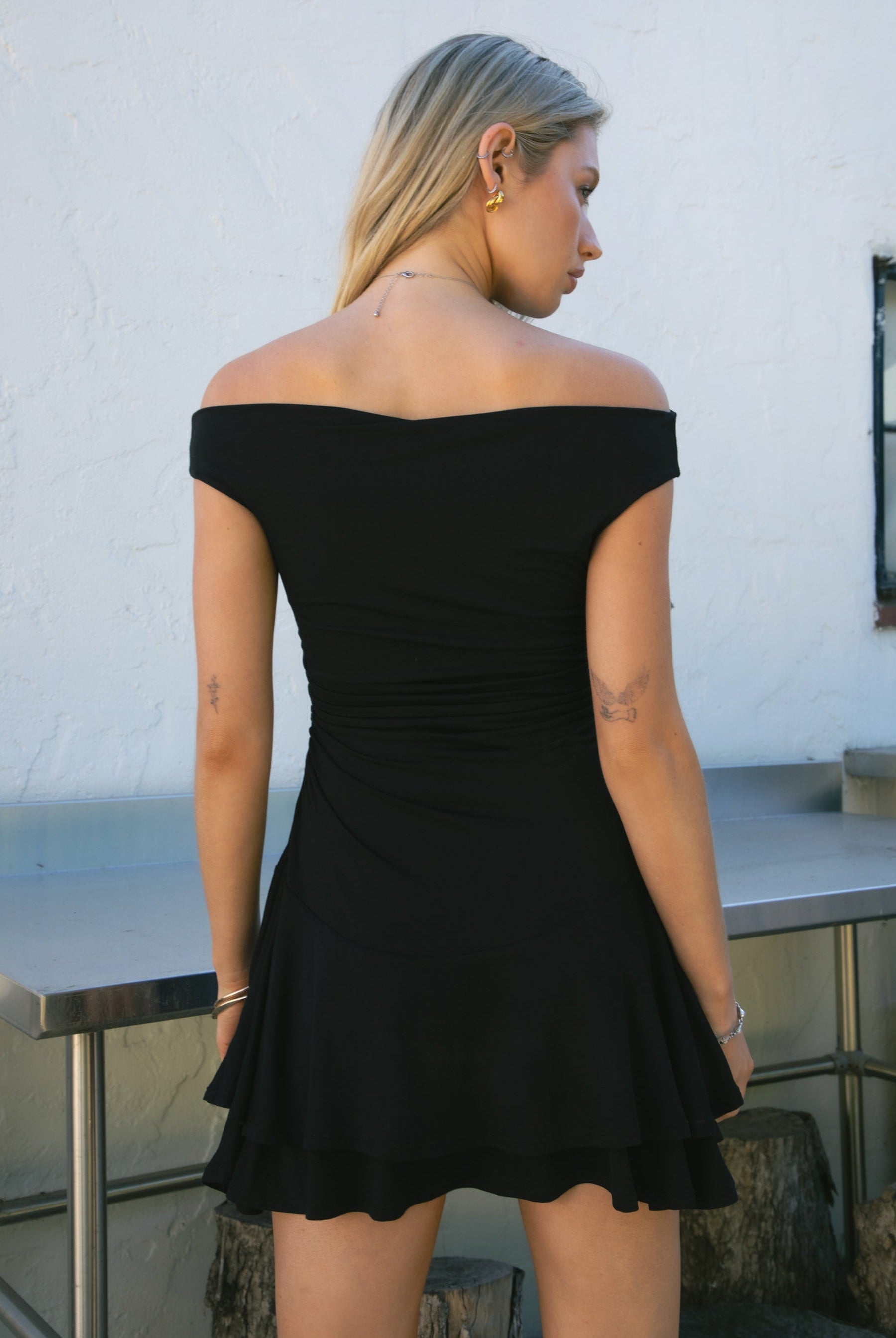 Woman wearing TIC TOC DC31642BA RAVAYA off-the-shoulder mini dress featuring ruched sides and a frill hemline in soft rayon spandex fabric