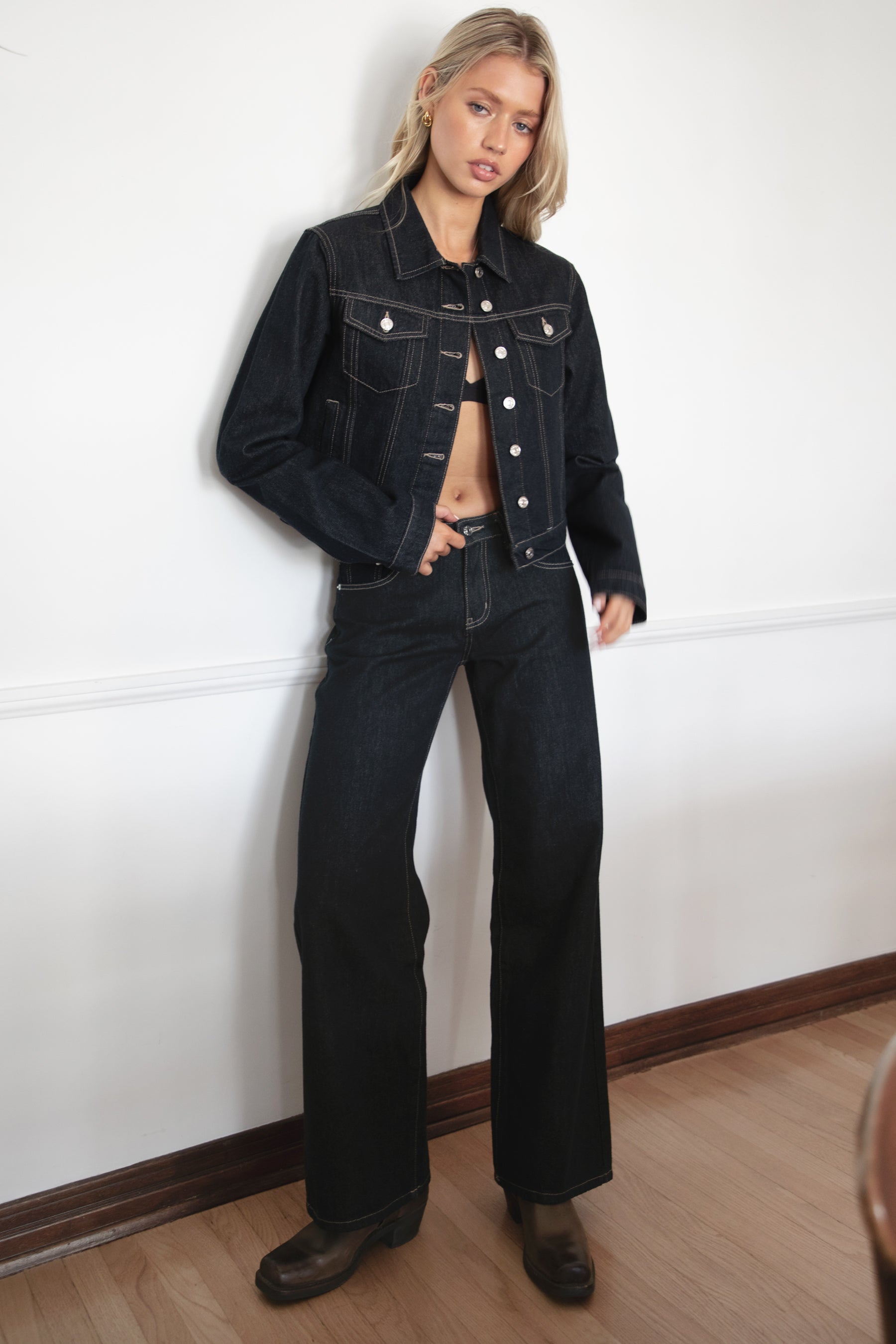 Woman wearing TIC TOC PF31703 MILLS selvedge denim straight leg pants in dark blue wash with a low-rise waist and wide-leg silhouette with a matching jackte in an indoor setting.
