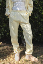 Woman wearing the TIC TOC PH26027 DOVE pale yellow high waist sweatpants featuring an elastic waistband, deep side pockets, and tapered ankle hem with a matching top.