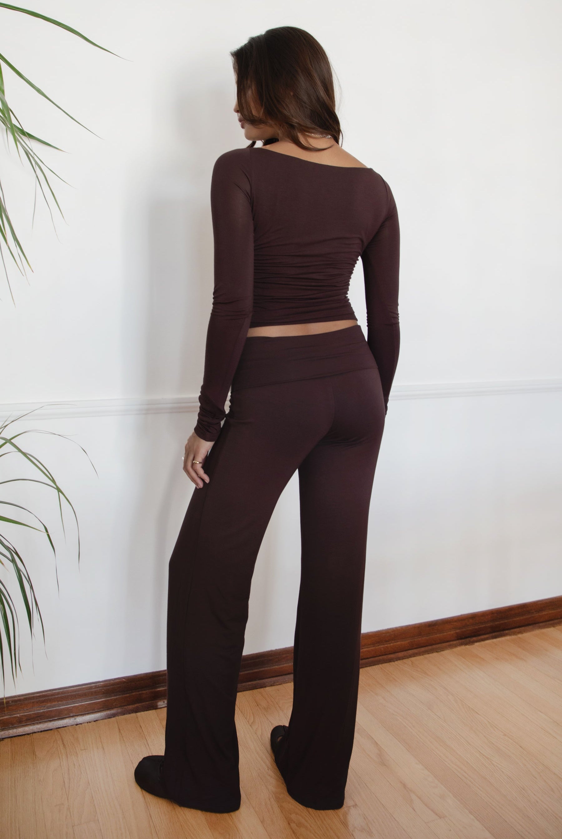 Woman wearing the TIC TOC PH31588BA SORA brown fold over straight leg leggings featuring a low rise waistline, smooth stretch fabric, and straight leg finish with the matching top against a white wall.