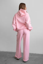 Woman wearing the TIC TOC PJ30241 LANI blush cloud fleece wide leg sweatpants featuring a straight leg silhouette, drawcord waistband, and side pockets paired with a matching sweater.