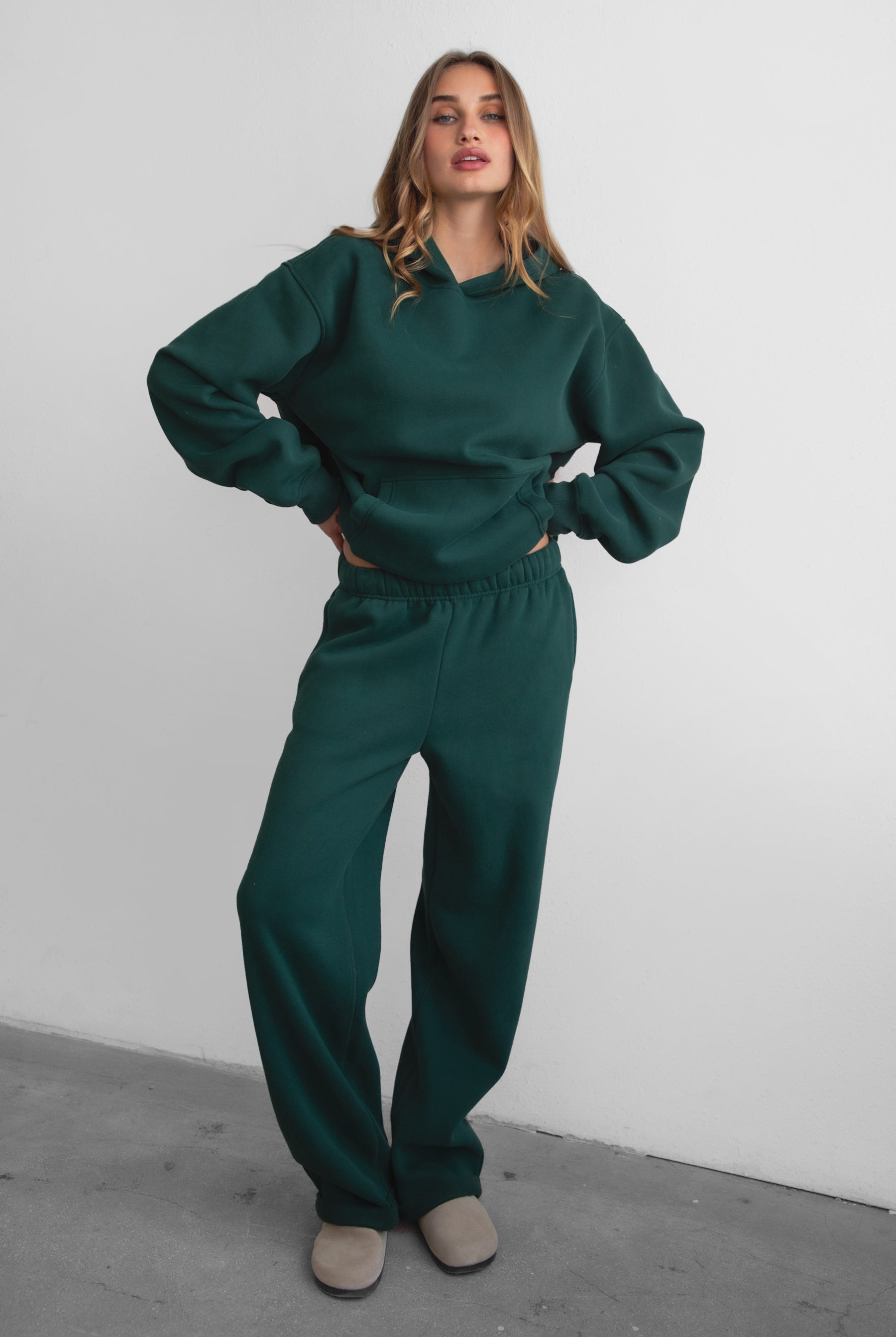 Woman wearing the TIC TOC PJ30241 LANI forrest green cloud fleece wide leg sweatpants featuring a straight leg silhouette, drawcord waistband, and side pockets paired with a matching sweater.