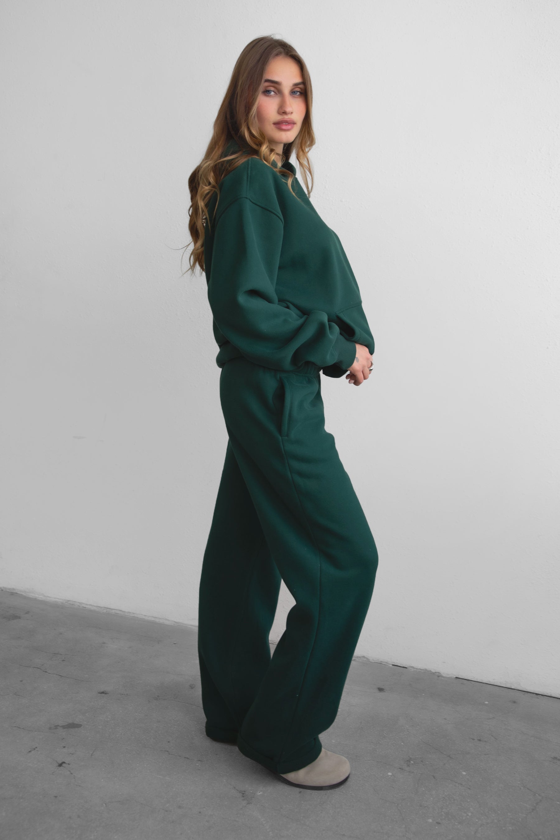 Woman wearing the TIC TOC PJ30241 LANI forrest green cloud fleece wide leg sweatpants featuring a straight leg silhouette, drawcord waistband, and side pockets paired with a matching sweater.