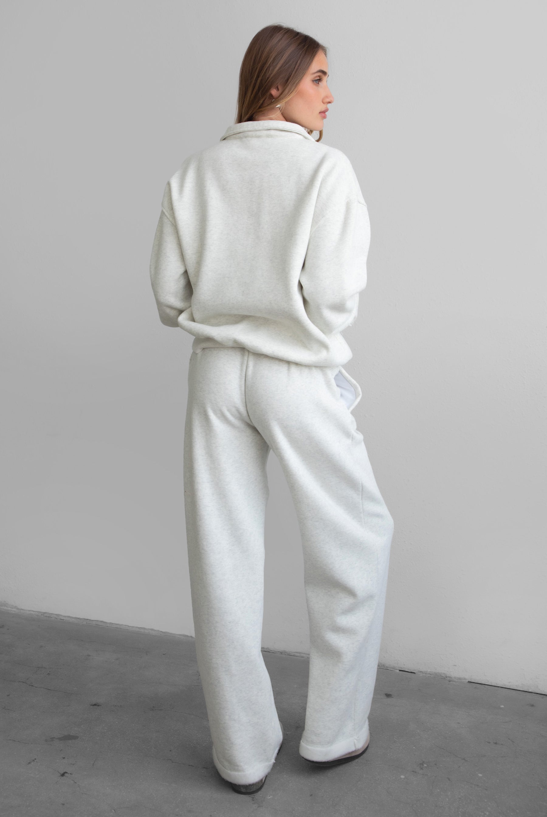 Woman wearing the TIC TOC PJ30241 LANI heather white cloud fleece wide leg sweatpants featuring a straight leg silhouette, drawcord waistband, and side pockets paired with a matching sweater.