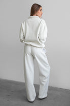Woman wearing the TIC TOC PJ30241 LANI heather white cloud fleece wide leg sweatpants featuring a straight leg silhouette, drawcord waistband, and side pockets paired with a matching sweater.
