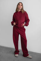 Woman wearing the TIC TOC PJ30241 LANI maroon cloud fleece wide leg sweatpants featuring a straight leg silhouette, drawcord waistband, and side pockets paired with a matching sweater.