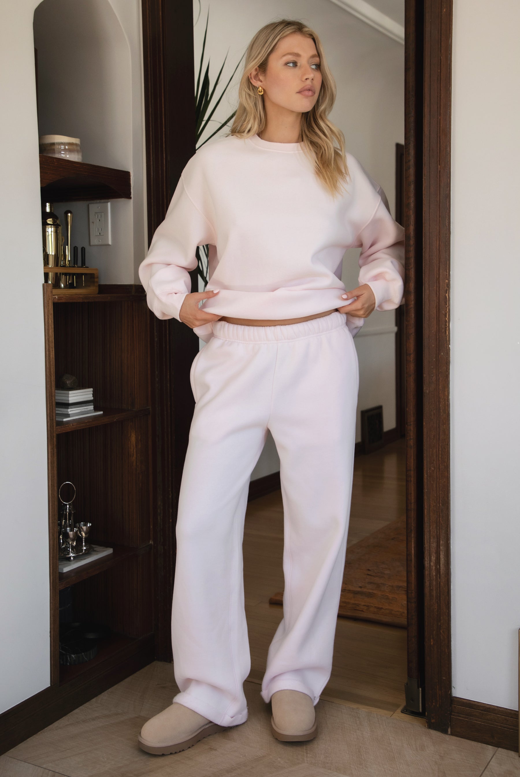 Woman wearing the TIC TOC PJ30241 LANI pale pink cloud fleece wide leg sweatpants featuring a straight leg silhouette, drawcord waistband, and side pockets paired with a matching sweater.