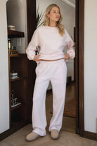 Woman wearing the TIC TOC PJ30241 LANI pale pink cloud fleece wide leg sweatpants featuring a straight leg silhouette, drawcord waistband, and side pockets paired with a matching sweater.