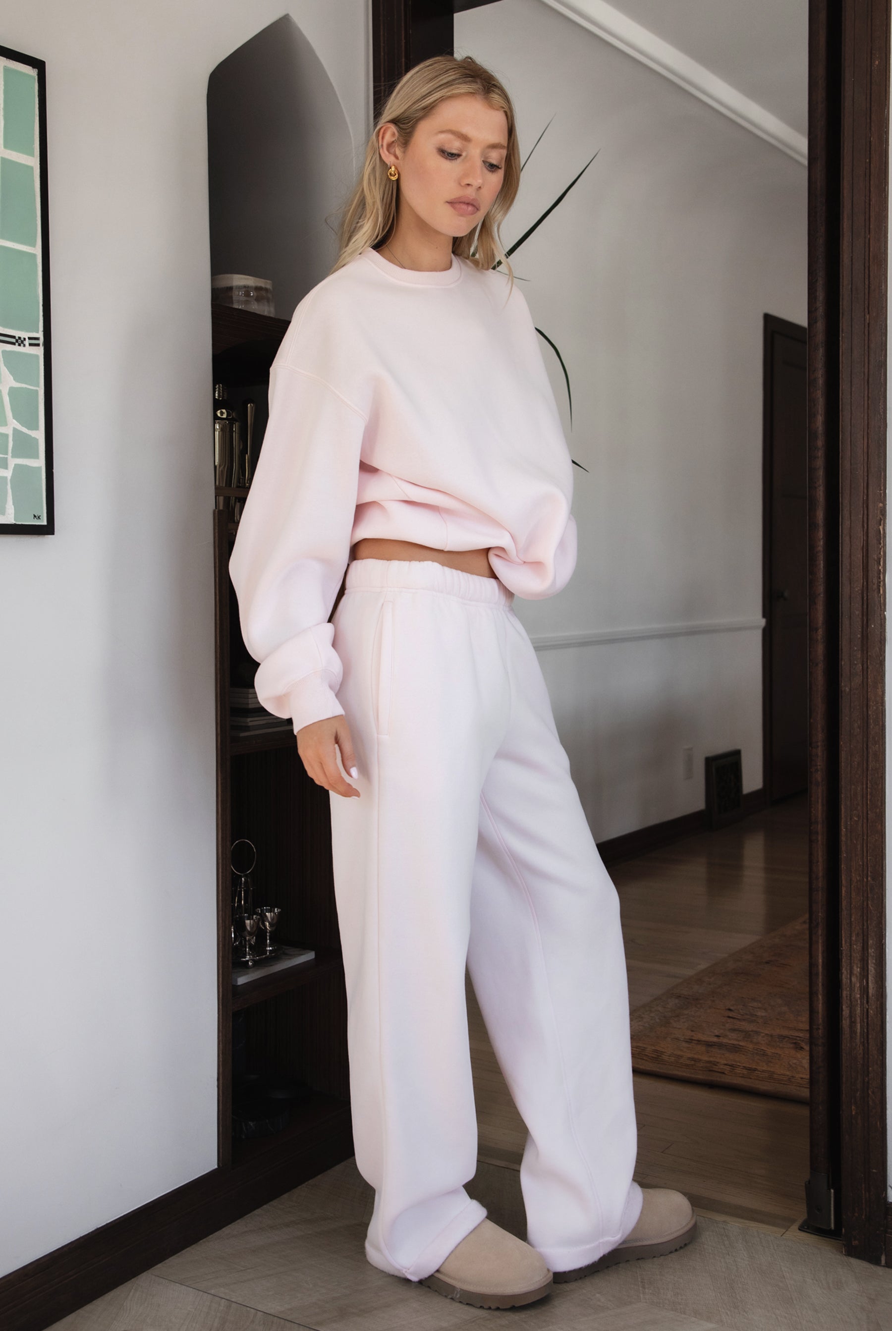 Woman wearing the TIC TOC PJ30241 LANI pale pink cloud fleece wide leg sweatpants featuring a straight leg silhouette, drawcord waistband, and side pockets paired with a matching sweater.
