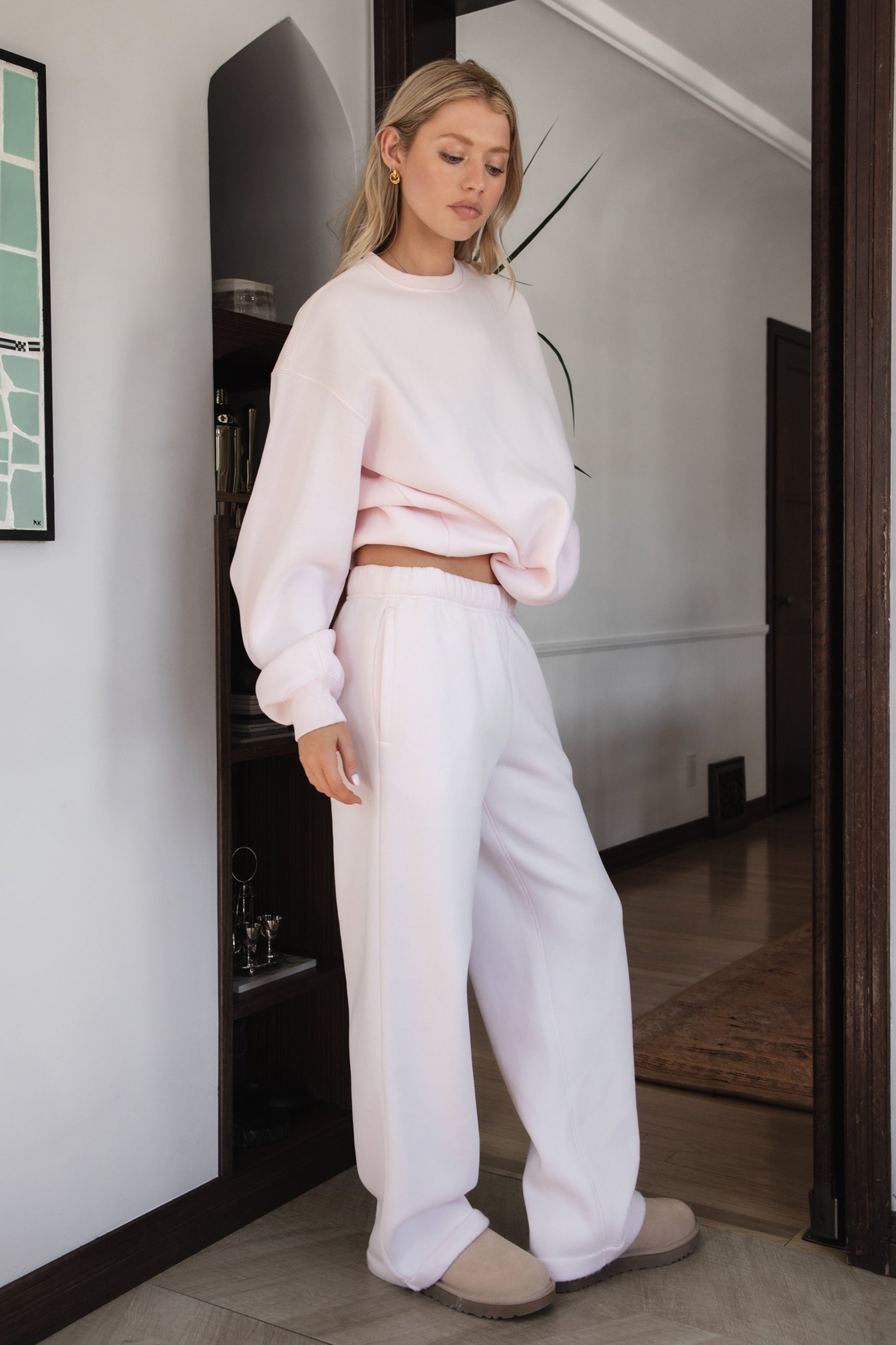 Woman wearing the TIC TOC PJ30241 LANI pale pink cloud fleece wide leg sweatpants featuring a straight leg silhouette, drawcord waistband, and side pockets paired with a matching sweater.