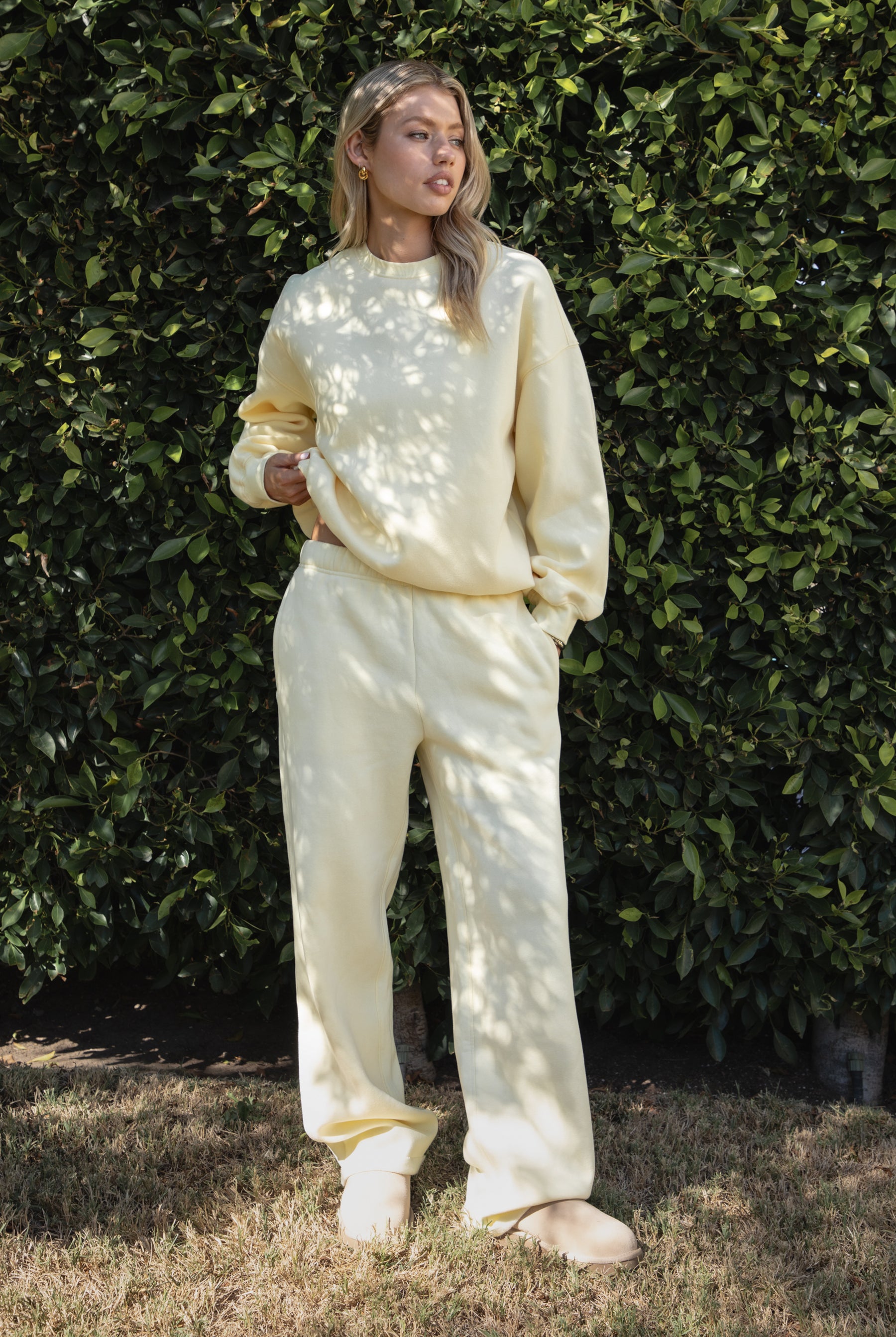 Woman wearing the TIC TOC PJ30241 LANI pale yellow cloud fleece wide leg sweatpants featuring a straight leg silhouette, drawcord waistband, and side pockets paired with a matching sweater.