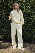 Woman wearing the TIC TOC PJ30241 LANI pale yellow cloud fleece wide leg sweatpants featuring a straight leg silhouette, drawcord waistband, and side pockets paired with a matching sweater.
