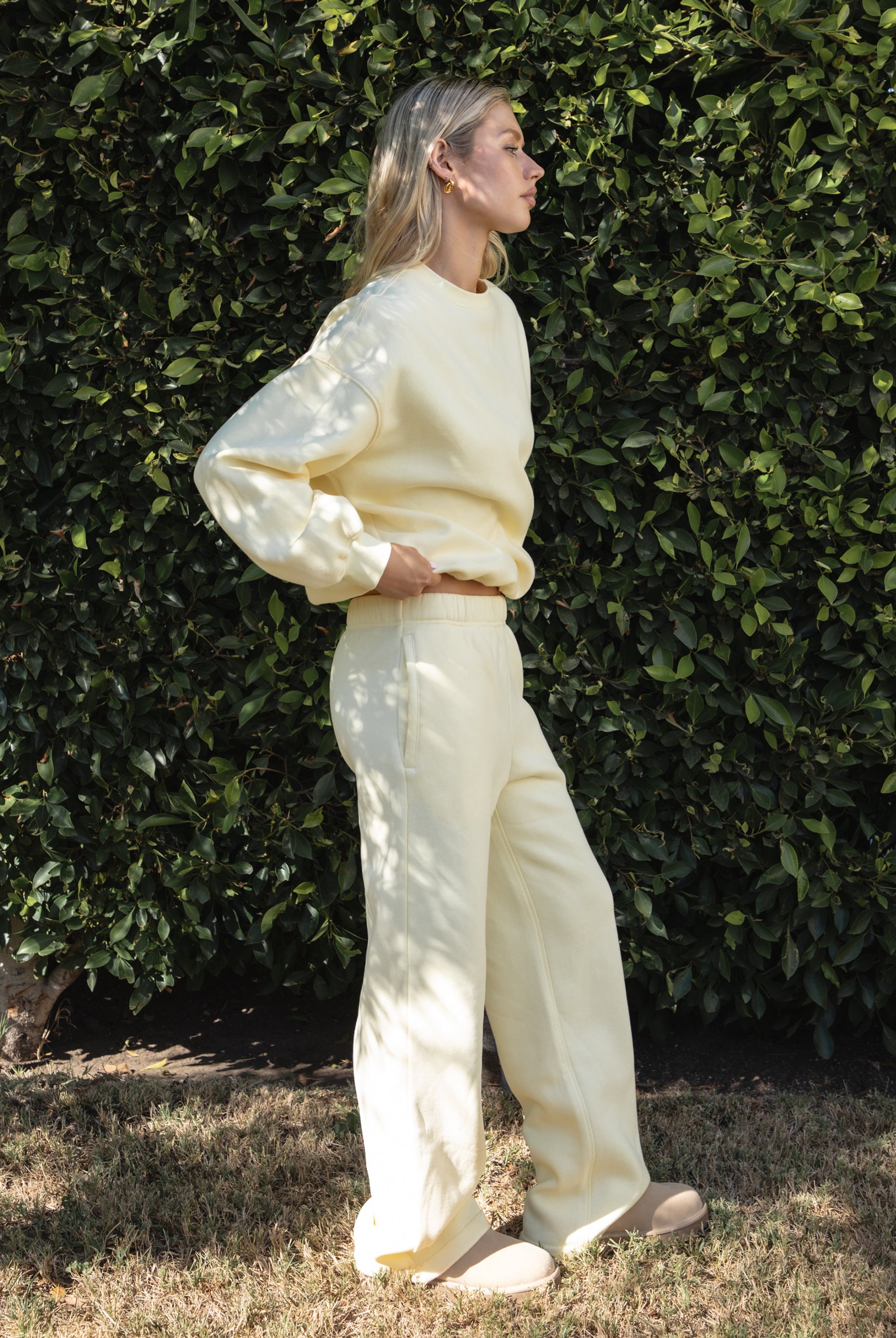Woman wearing the TIC TOC PJ30241 LANI pale yellow cloud fleece wide leg sweatpants featuring a straight leg silhouette, drawcord waistband, and side pockets paired with a matching sweater.