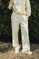 Woman wearing the TIC TOC PJ30241 LANI pale yellow cloud fleece wide leg sweatpants featuring a straight leg silhouette, drawcord waistband, and side pockets paired with a matching sweater.