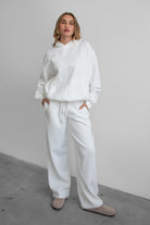 Woman wearing the TIC TOC PJ30241 LANI white cloud fleece wide leg sweatpants featuring a straight leg silhouette, drawcord waistband, and side pockets paired with a matching sweater.