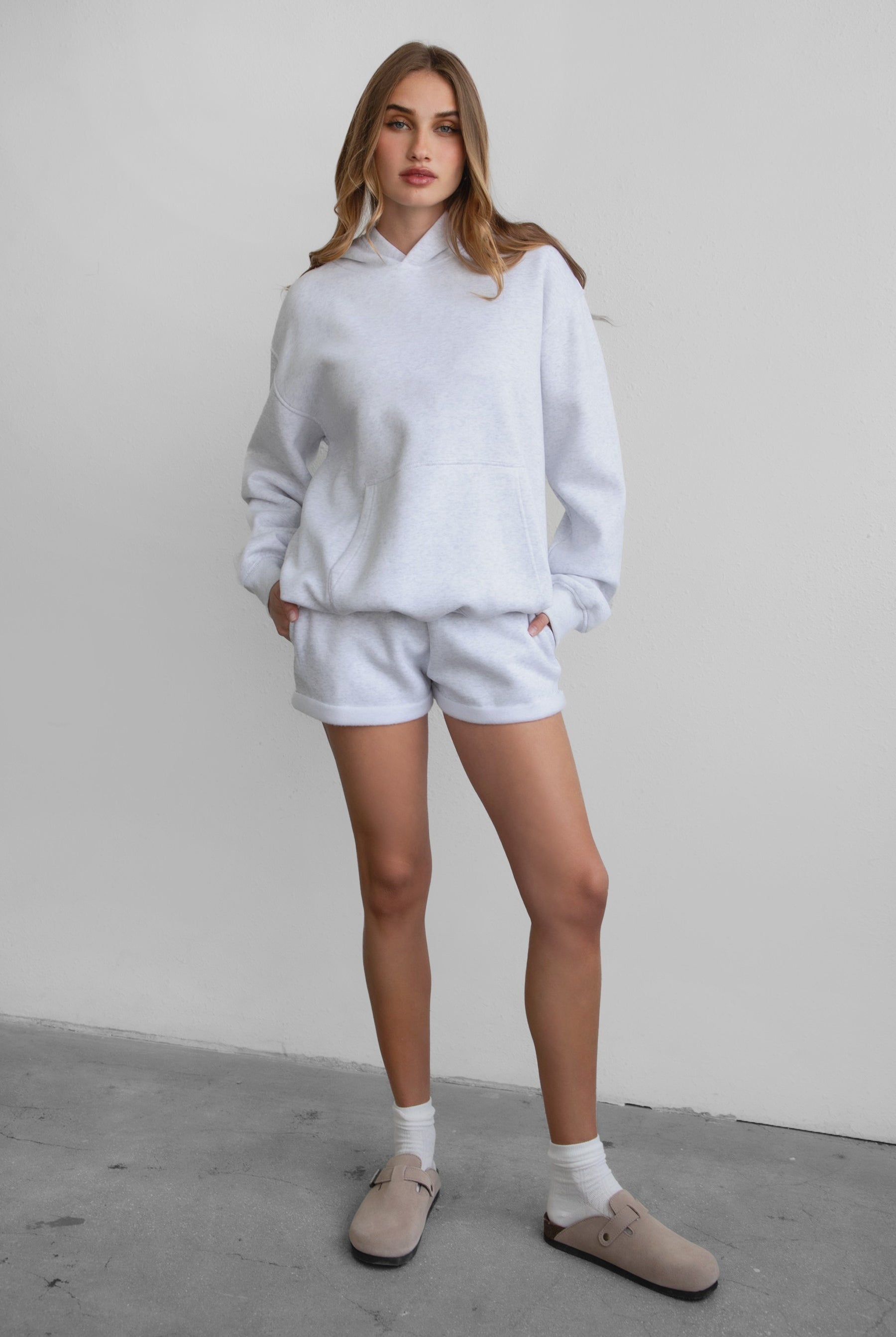 Woman wearing the TIC TOC PJ31004 CARLY ash cloud fleece low rise shorts featuring an elastic waistband with drawcord, deep side pockets, and raw cut hemline paired with a matching top