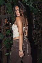 Woman wearing the TIC TOC TA31523 SADELIA khaki stretch suede embroidered strapless top featuring western embroidery, lace-up back, and curved hem paired with brown denim pants.