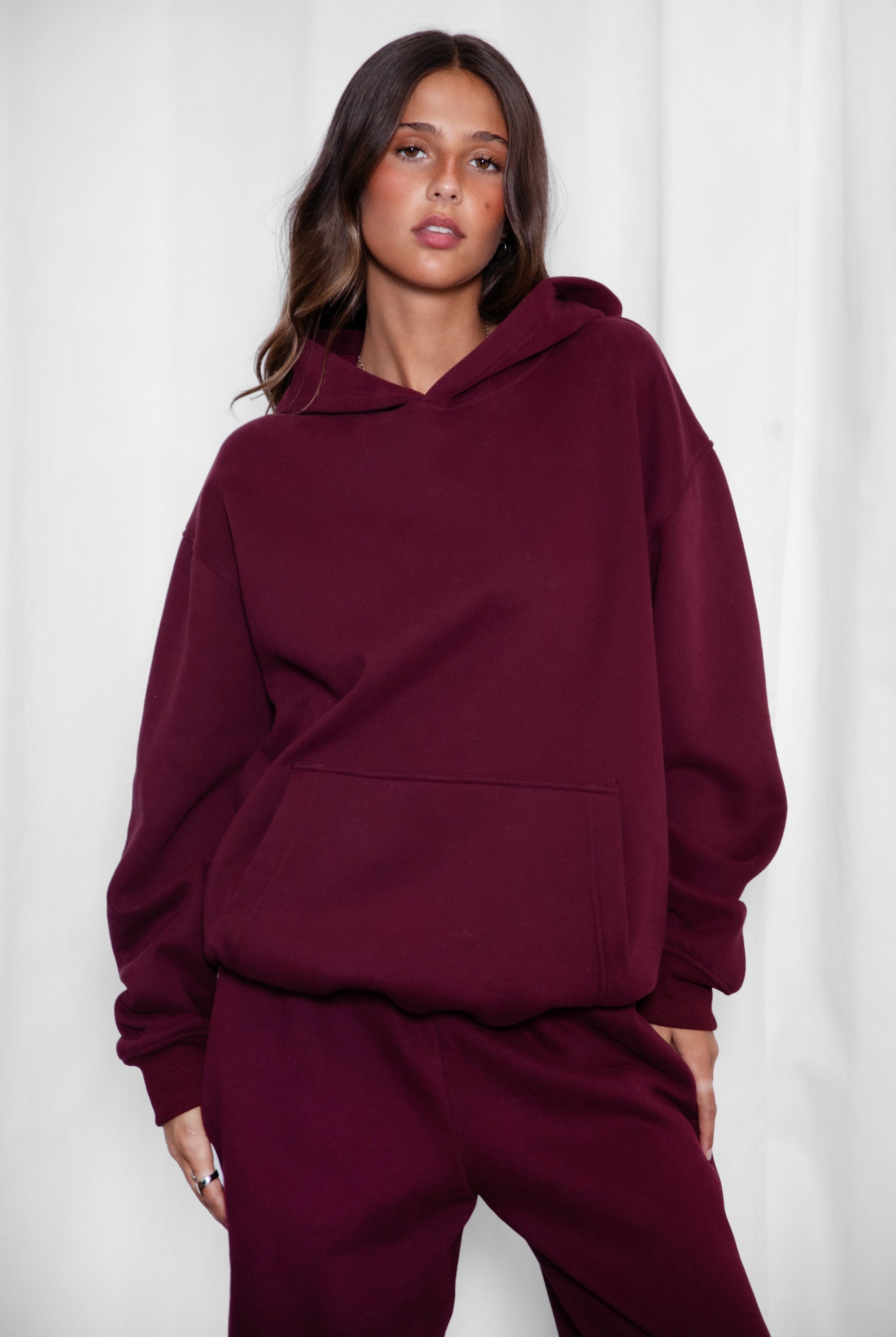 Woman wearing the TIC TOC TJ31007 DAMI black cherry cloud fleece oversized hoodie featuring a dropped shoulder design, kangaroo pocket, and ribbed cuffs with matching bottoms.