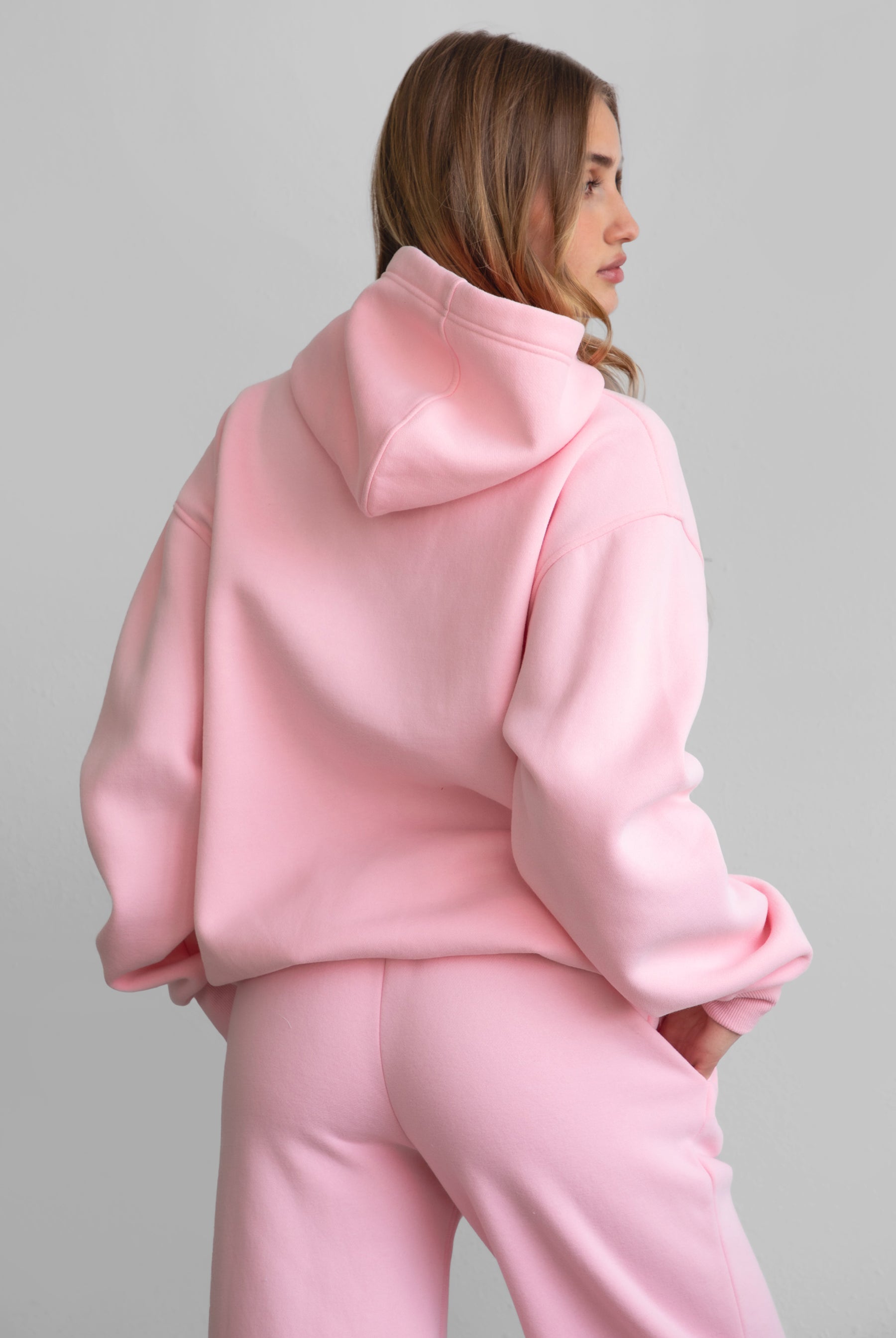 Woman wearing the TIC TOC TJ31007 DAMI blush cloud fleece oversized hoodie featuring a dropped shoulder design, kangaroo pocket, and ribbed cuffs with matching bottoms.