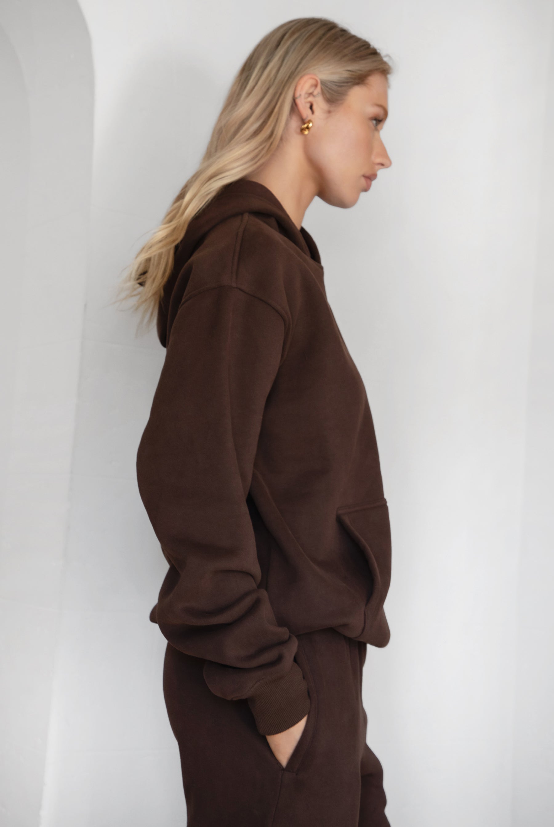 Woman wearing the TIC TOC TJ31007 DAMI dark brown cloud fleece oversized hoodie featuring a dropped shoulder design, kangaroo pocket, and ribbed cuffs with matching bottoms.