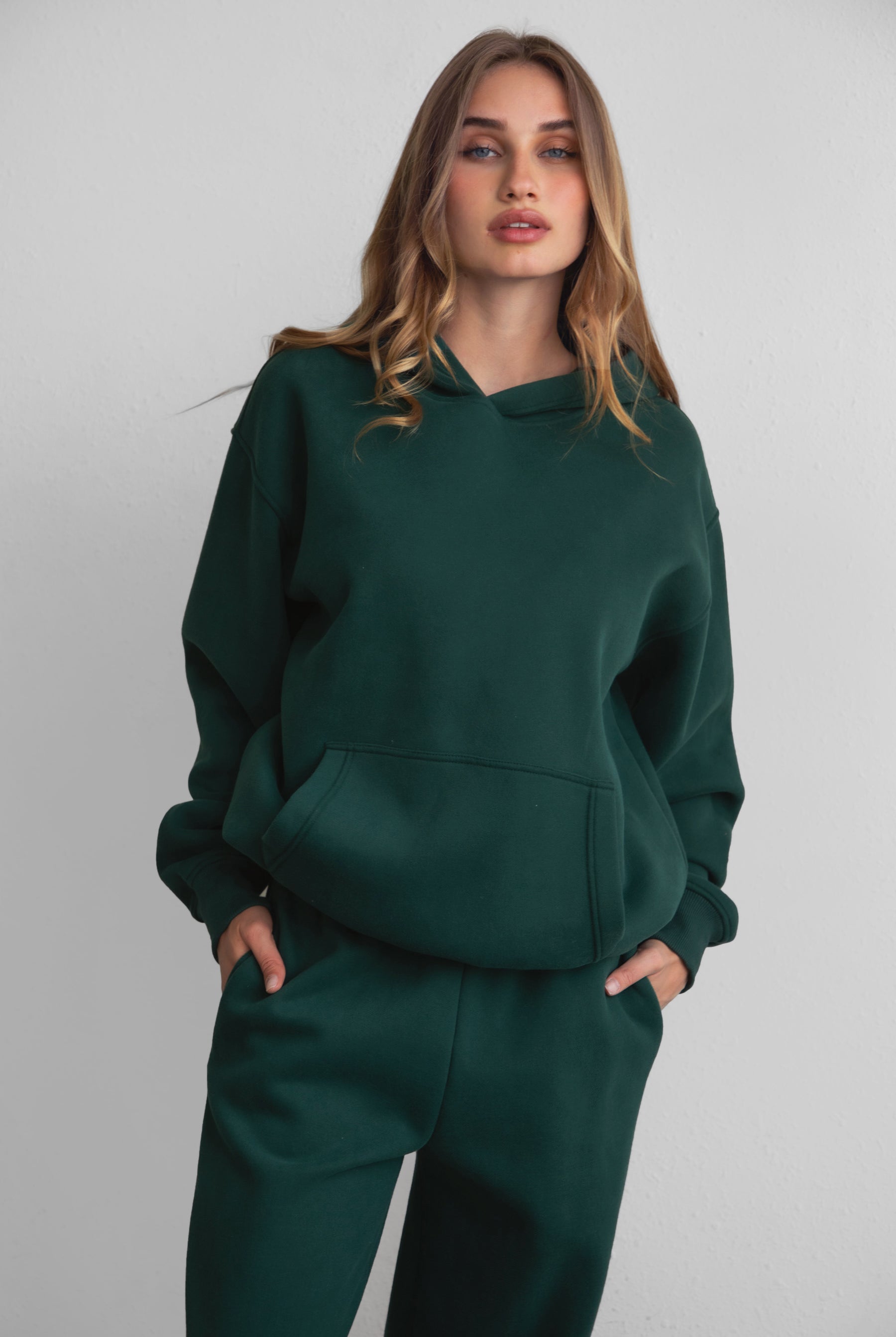 Woman wearing the TIC TOC TJ31007 DAMI forrest green cloud fleece oversized hoodie featuring a dropped shoulder design, kangaroo pocket, and ribbed cuffs with matching bottoms.